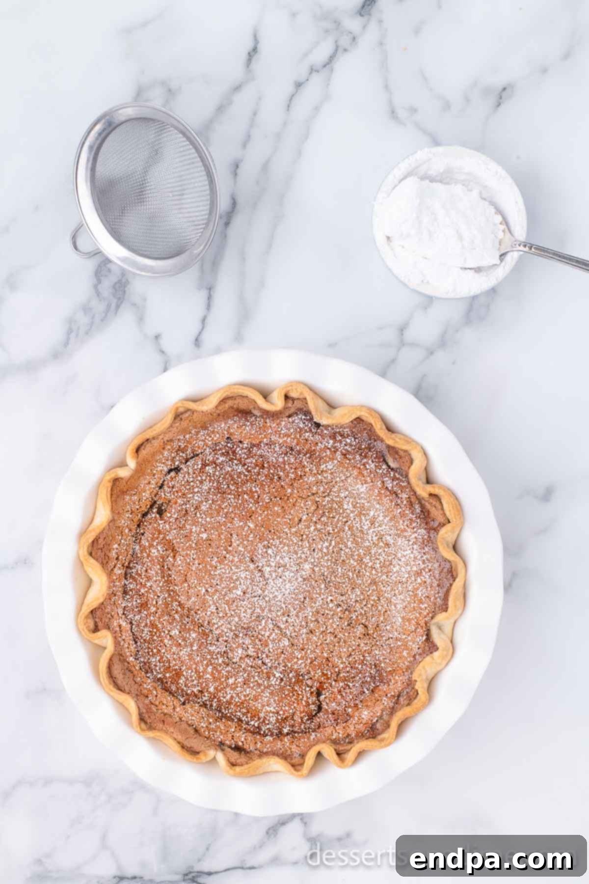 A freshly baked cinnamon pie, cooled and elegantly dusted with powdered sugar, ready to be sliced and served.