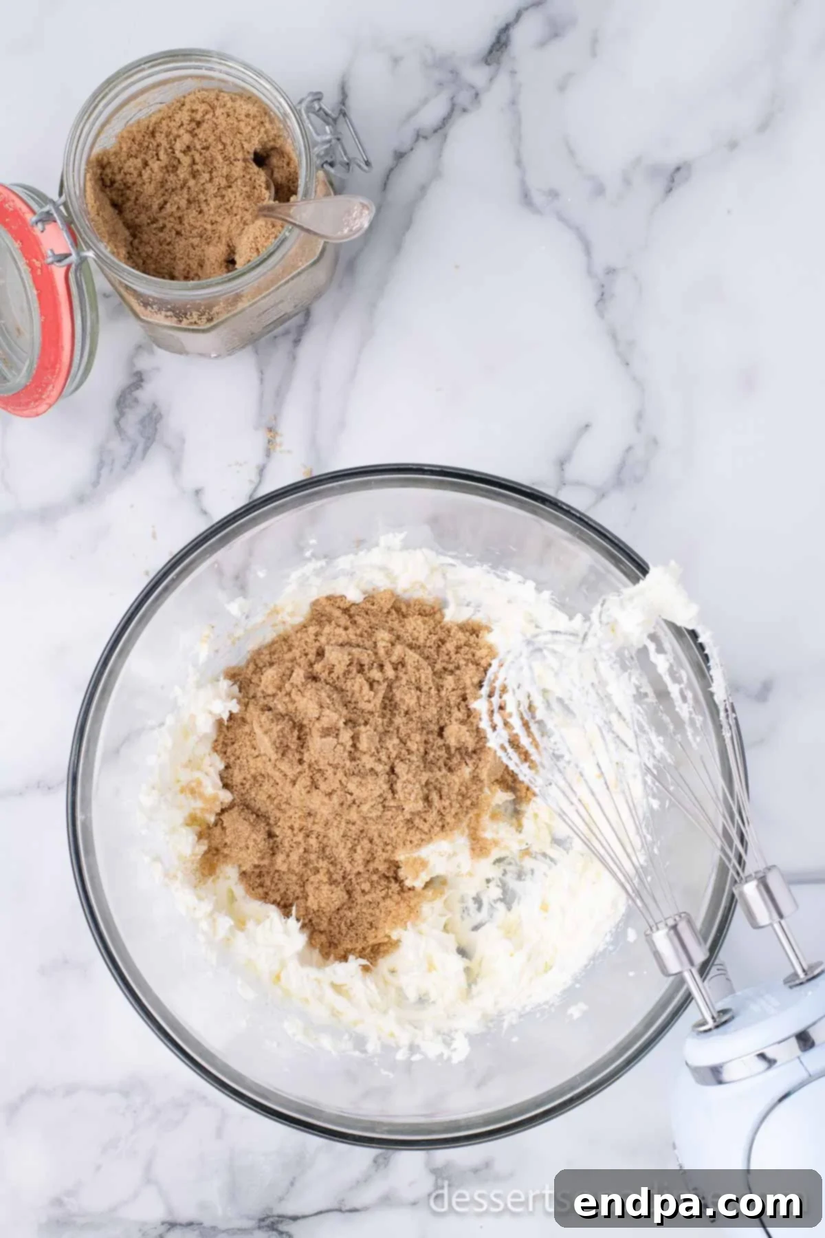 A large mixing bowl containing softened cream cheese and packed brown sugar, ready to be beaten together.
