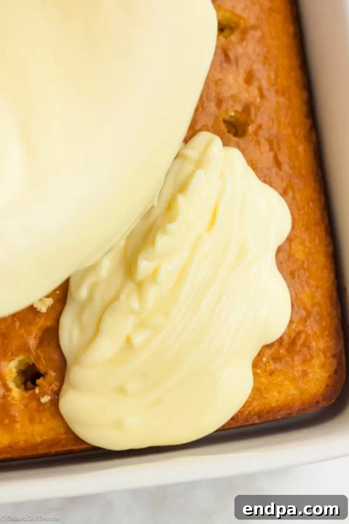 Banana Dream Pudding Cake 5 The pudding mixture being poured on top of the vanilla cake poked with holes