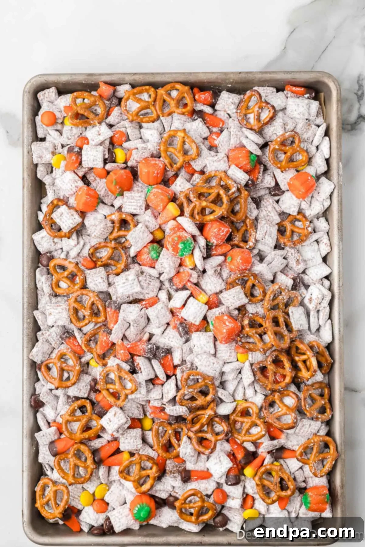 Autumn mix candies and pretzel twists being added to the Puppy Chow.