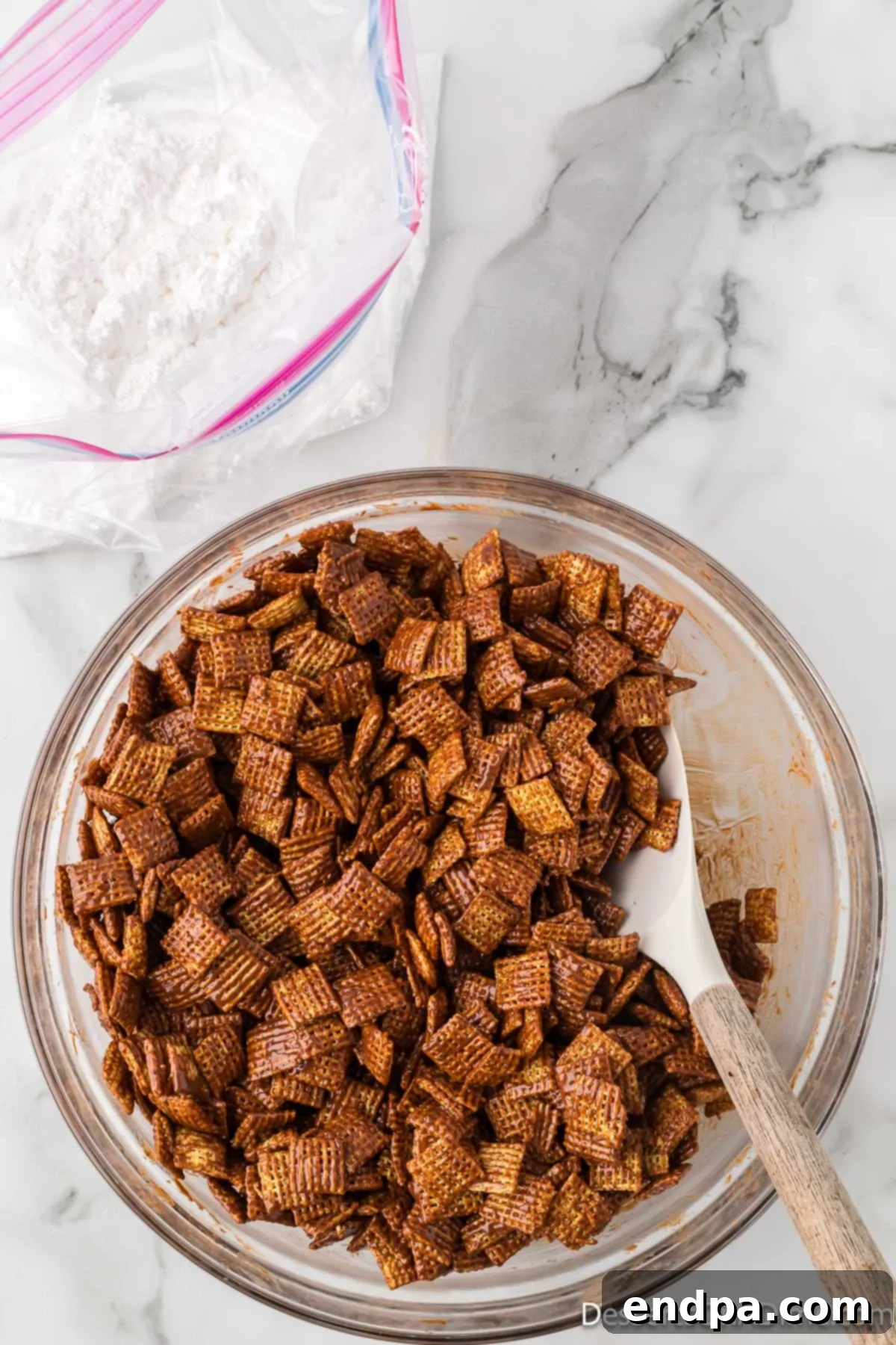 Cereal being gently folded with a spatula to evenly coat it in the chocolate mixture.