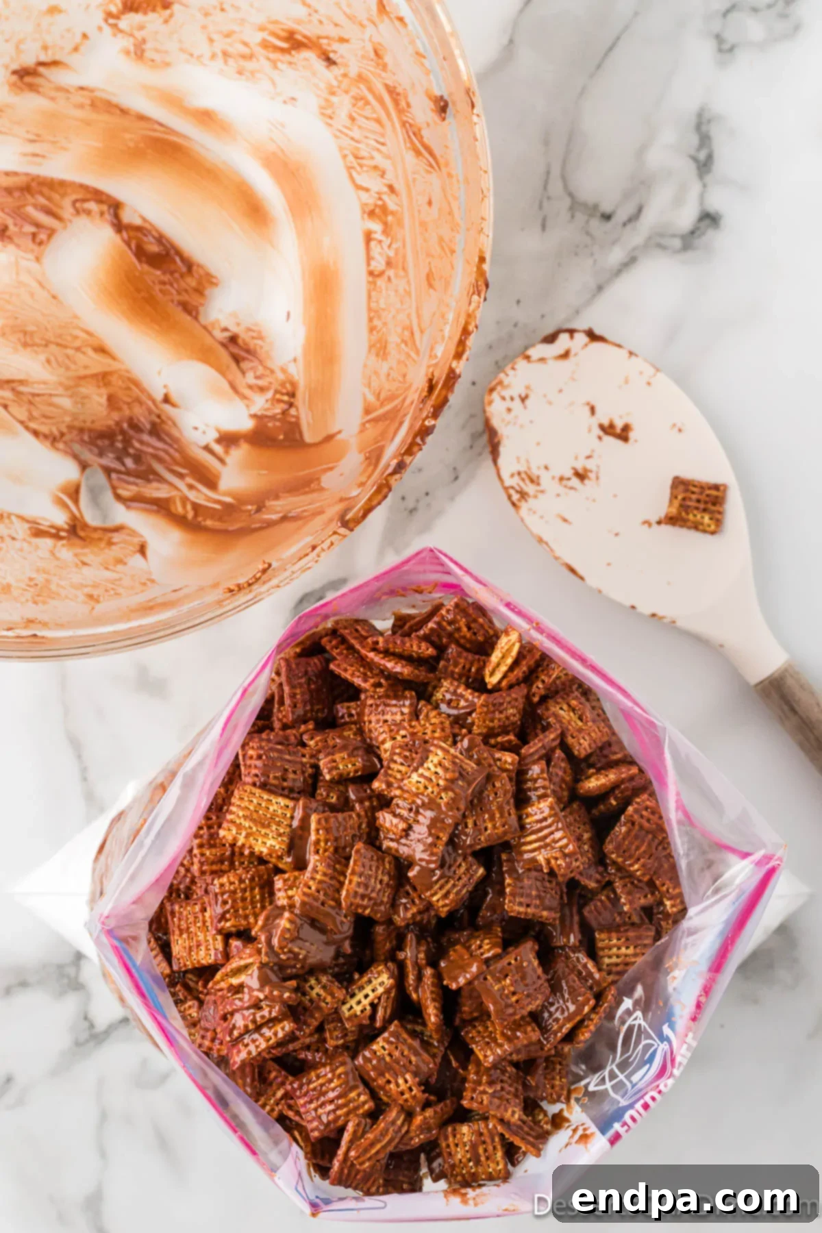 Chocolate-coated Chex cereal being transferred into a large Ziploc bag containing powdered sugar.