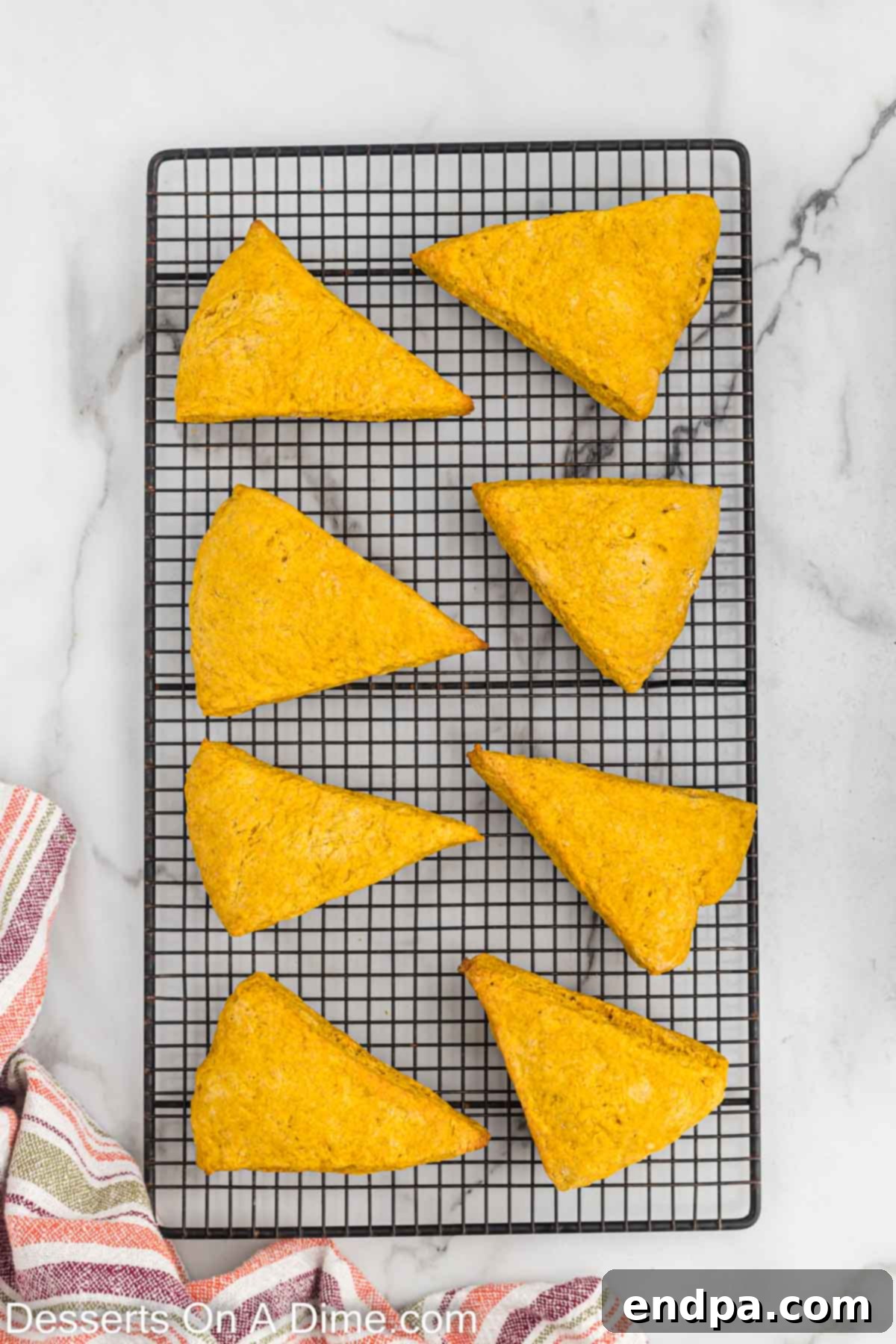 Freshly baked pumpkin scones cooling on a wire rack at room temperature, allowing them to firm up before glazing.