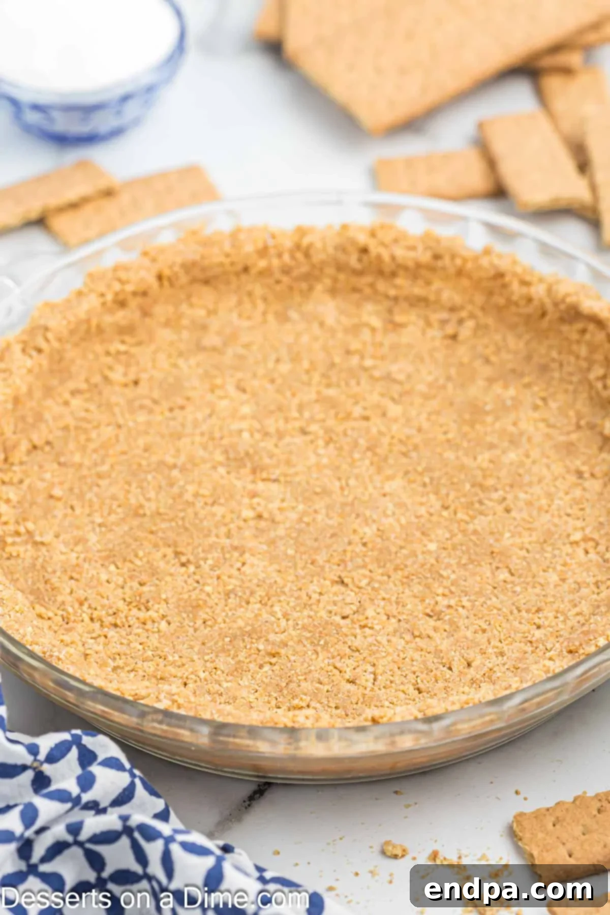 Golden brown homemade graham cracker crust in a glass pie plate, ready for filling. The crust is evenly pressed and appears perfectly baked.