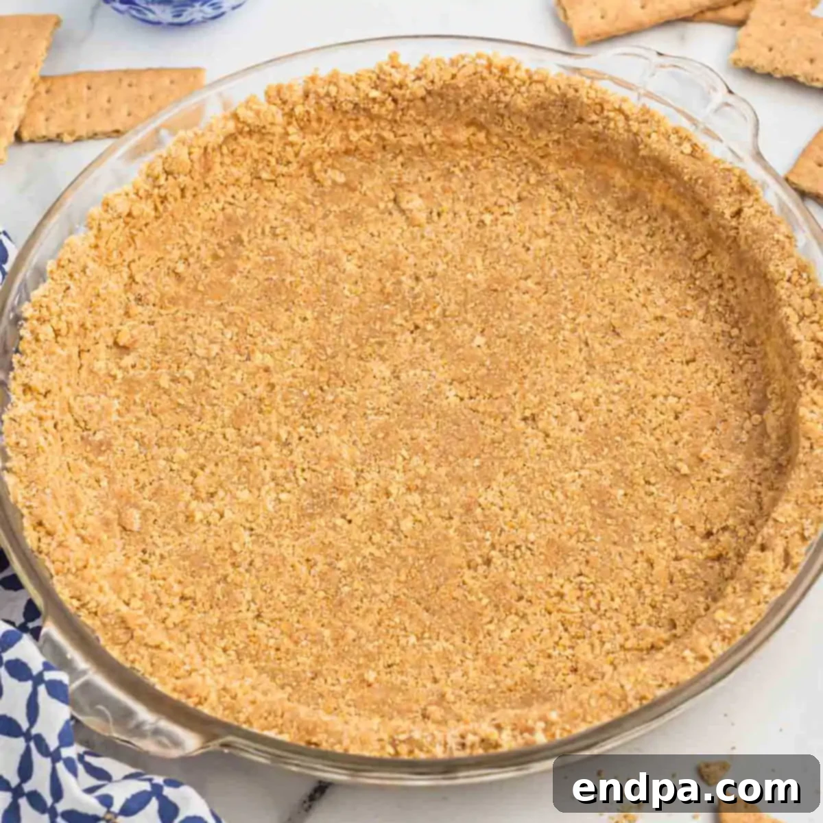 A completed graham cracker crust, golden brown and perfectly set in a pie plate, ready to be filled.