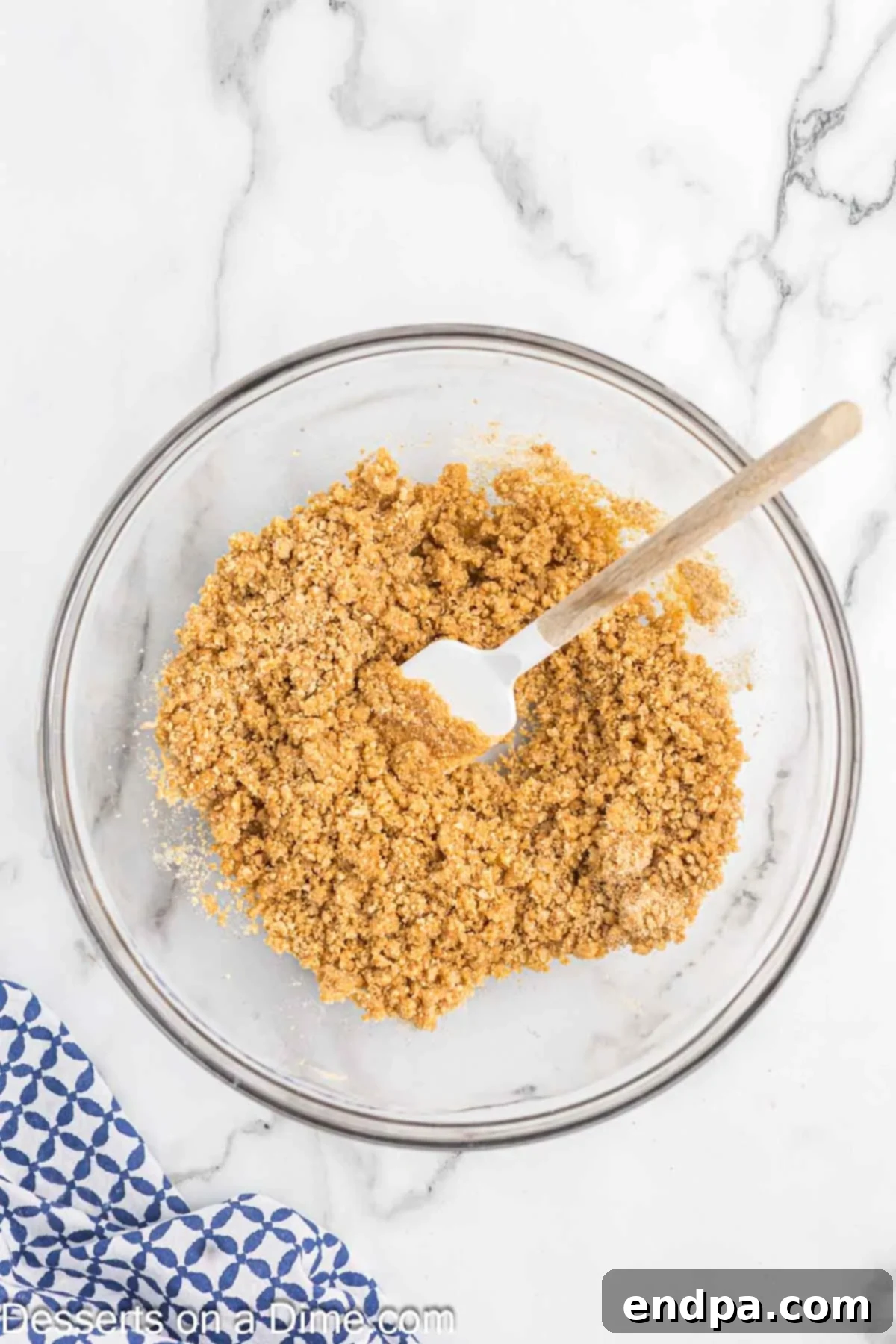 Melted butter being poured over the graham cracker, sugar, and salt mixture in a bowl, showing the binding process.