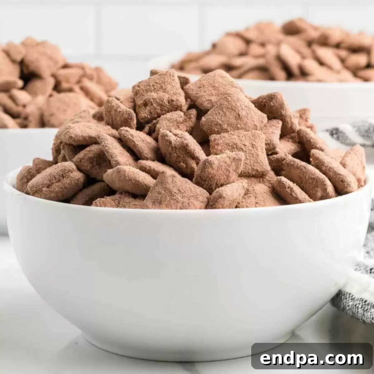 Double Fudge Brownie Crunch 12 Delicious Brownie Puppy Chow in a square serving dish.