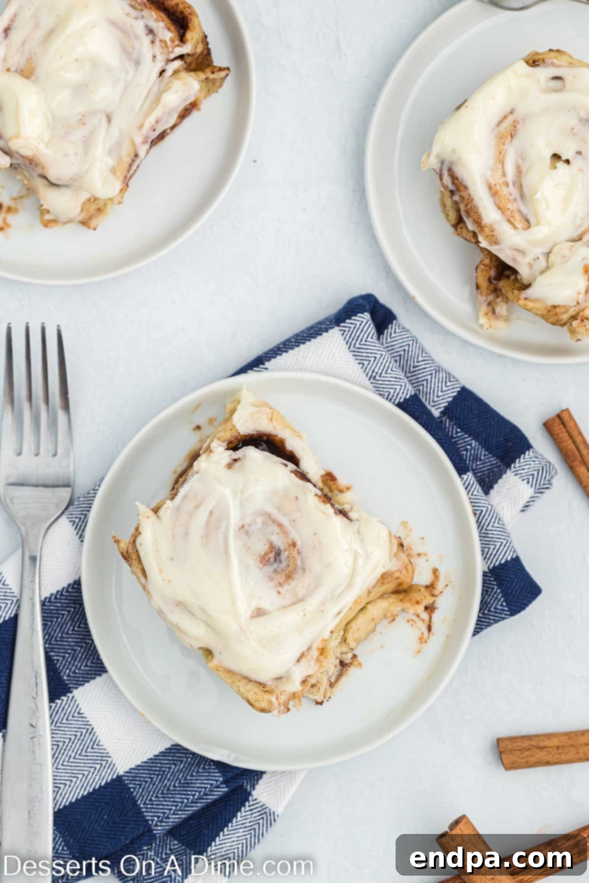 Crafting Perfect Cinnabon Cinnamon Rolls 2 Freshly baked Cinnabon Cinnamon Rolls on a plate, generously covered with cream cheese frosting.