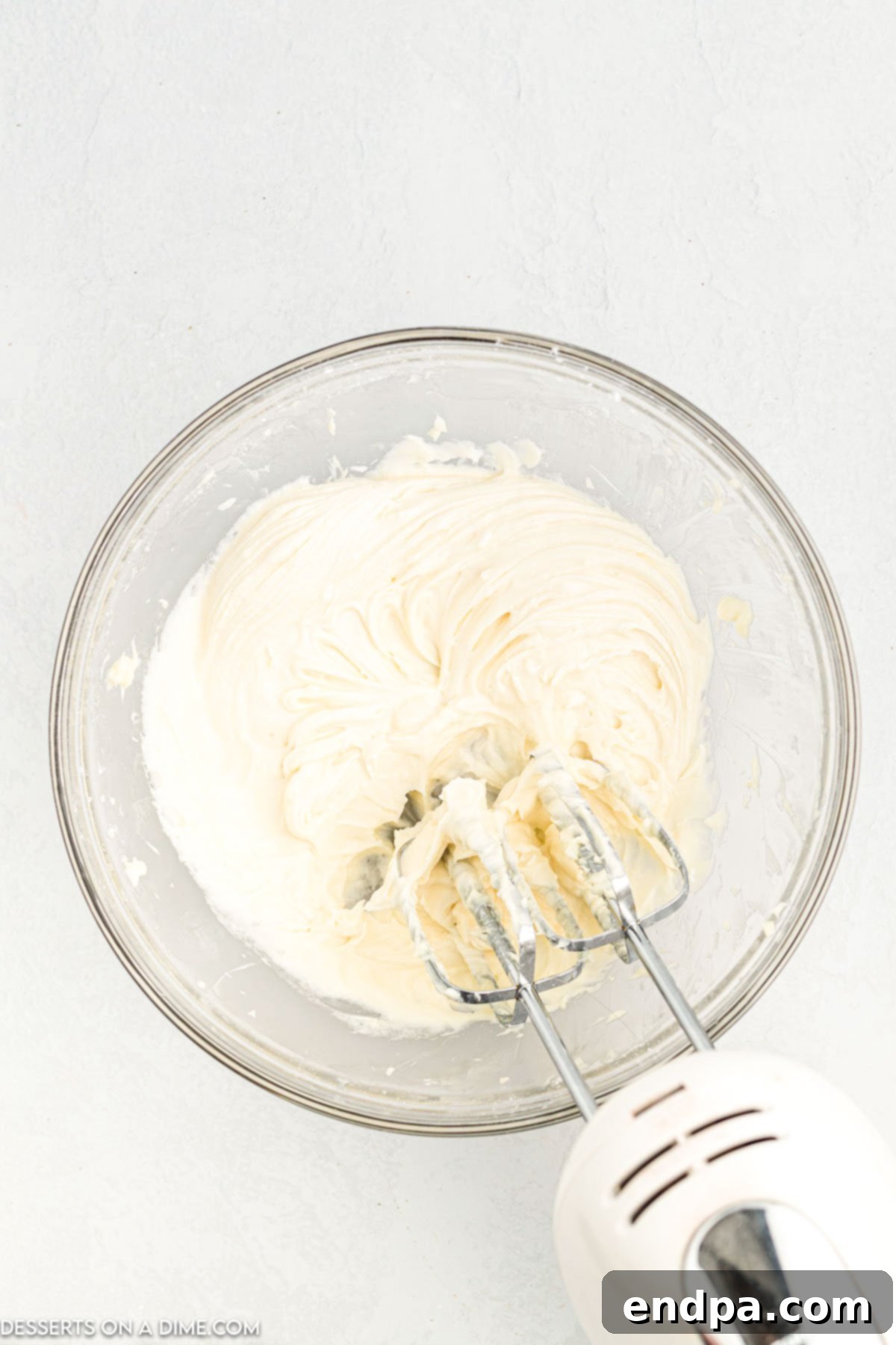 Crafting Perfect Cinnabon Cinnamon Rolls 11 Cream cheese, powdered sugar, butter, and vanilla extract being combined in a bowl to make the decadent frosting.