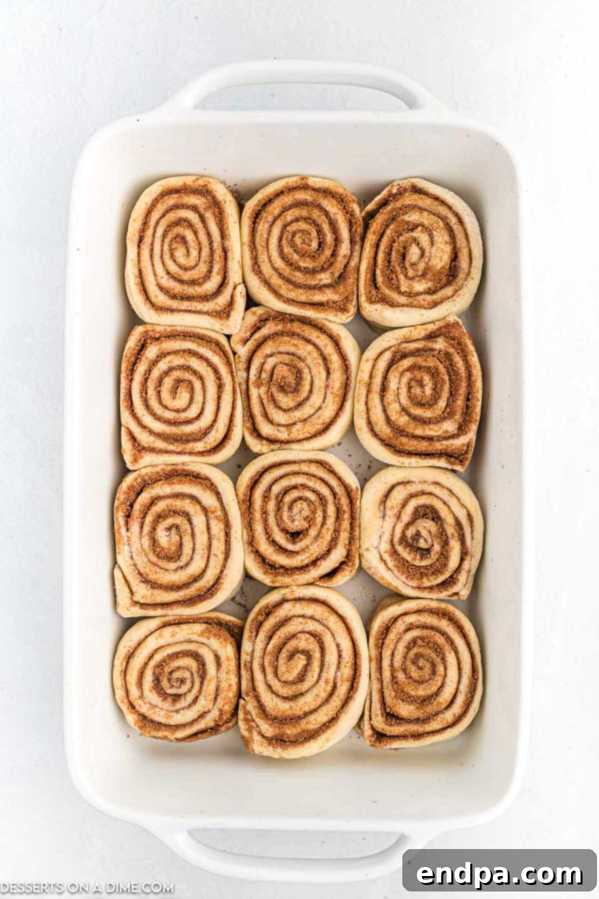 Crafting Perfect Cinnabon Cinnamon Rolls 10 Unbaked Cinnabon Cinnamon Rolls arranged in a 9x13 inch baking dish, ready for their second rise and baking.