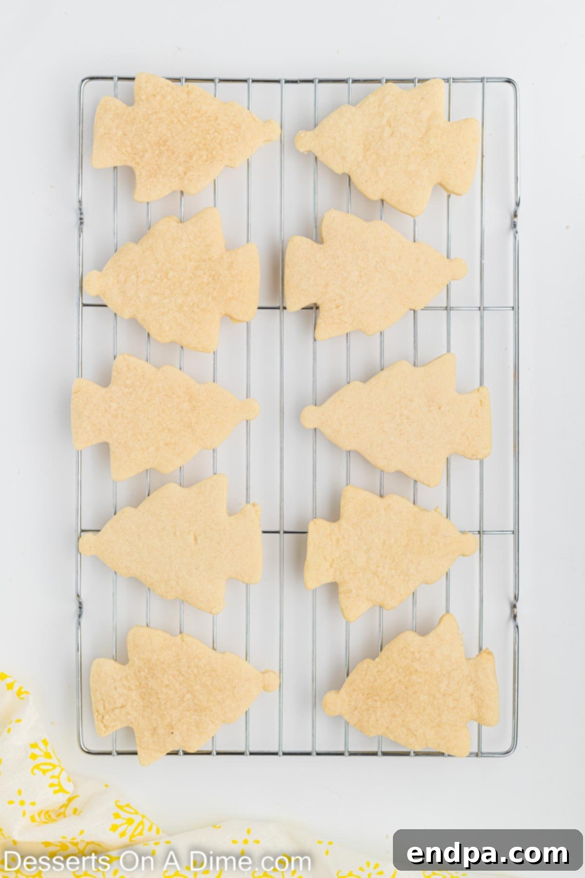Holiday Tree Sugar Cookie Delights 7 Baked Christmas tree sugar cookies cooling on a wire rack after being removed from the oven.