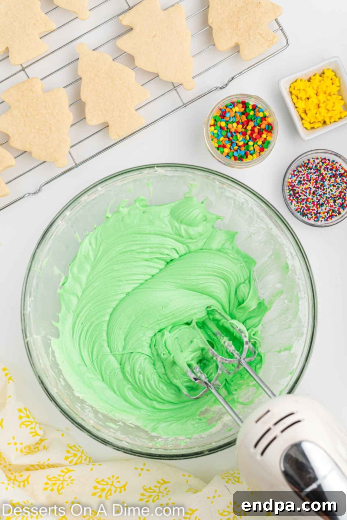Holiday Tree Sugar Cookie Delights 10 Green gel food coloring being mixed into the prepared cream cheese frosting in a bowl, creating a vibrant green hue.