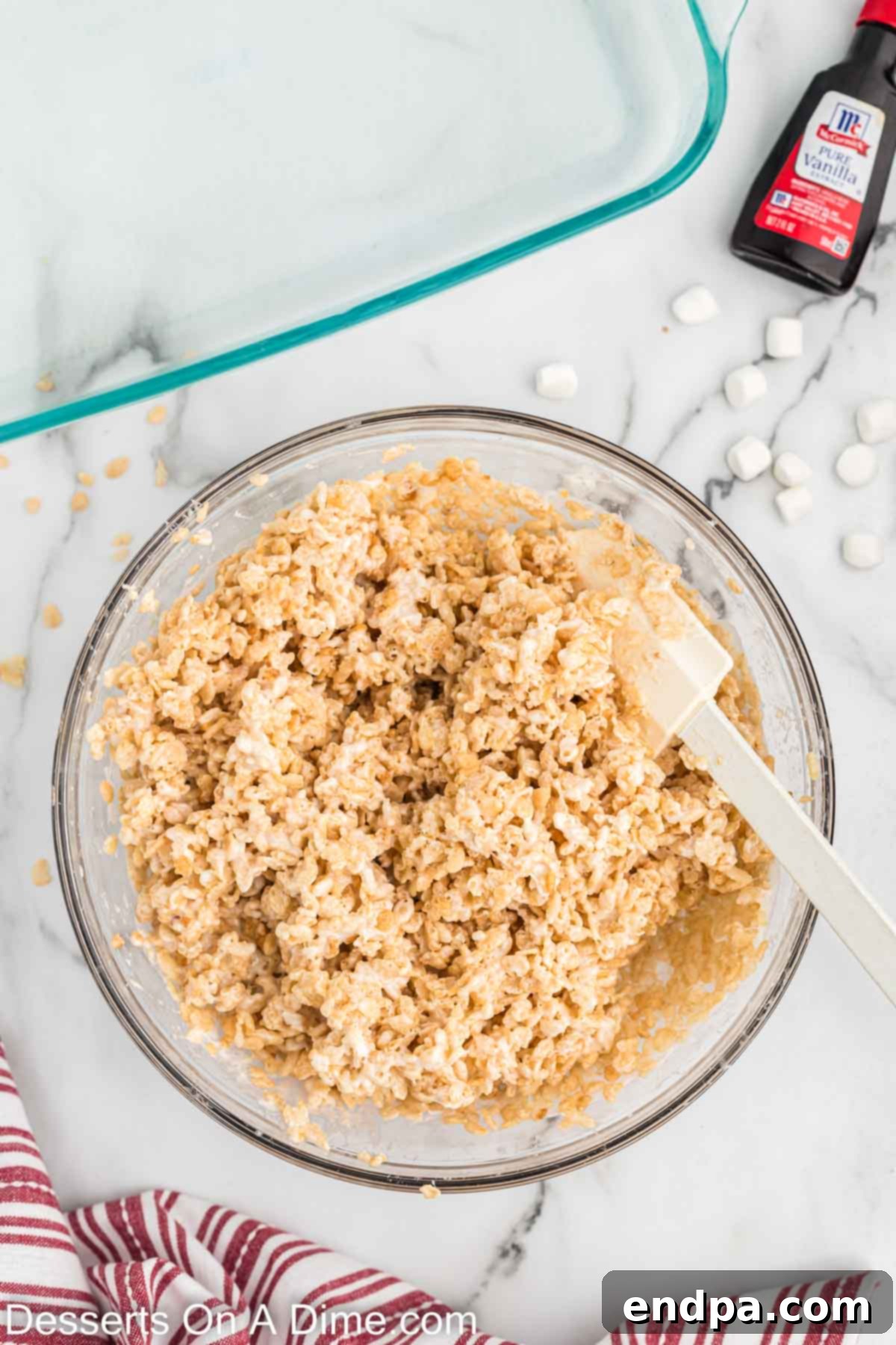 Rice Krispie cereal added to melted marshmallow mixture and combined in a bowl.