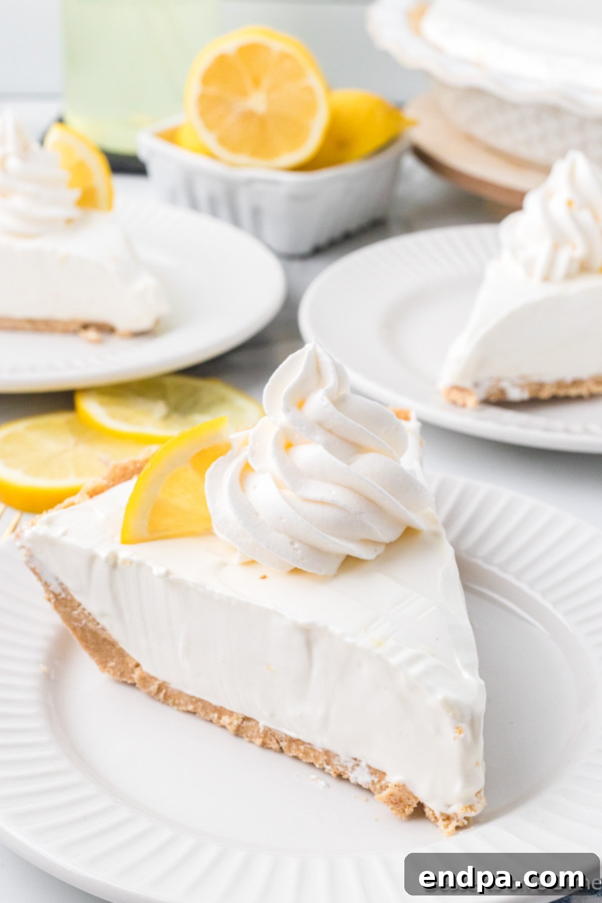 Cool Lemon Cloud Pie 2 A slice of Lemonade Pie on a white plate, garnished with lemon zest.