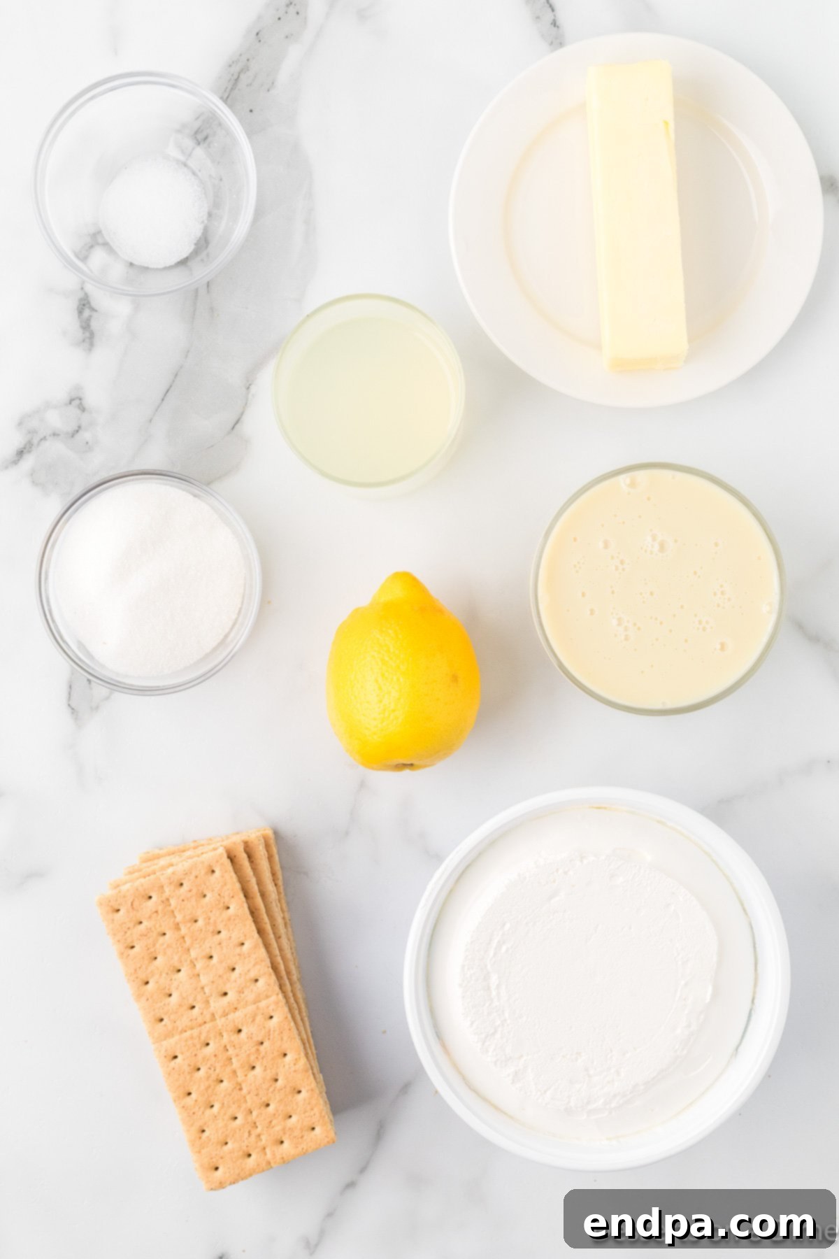 Cool Lemon Cloud Pie 3 A flat lay image showing ingredients for lemonade pie: graham cracker crumbs, a lemon zester with lemon zest, whipped cream, and a bowl.