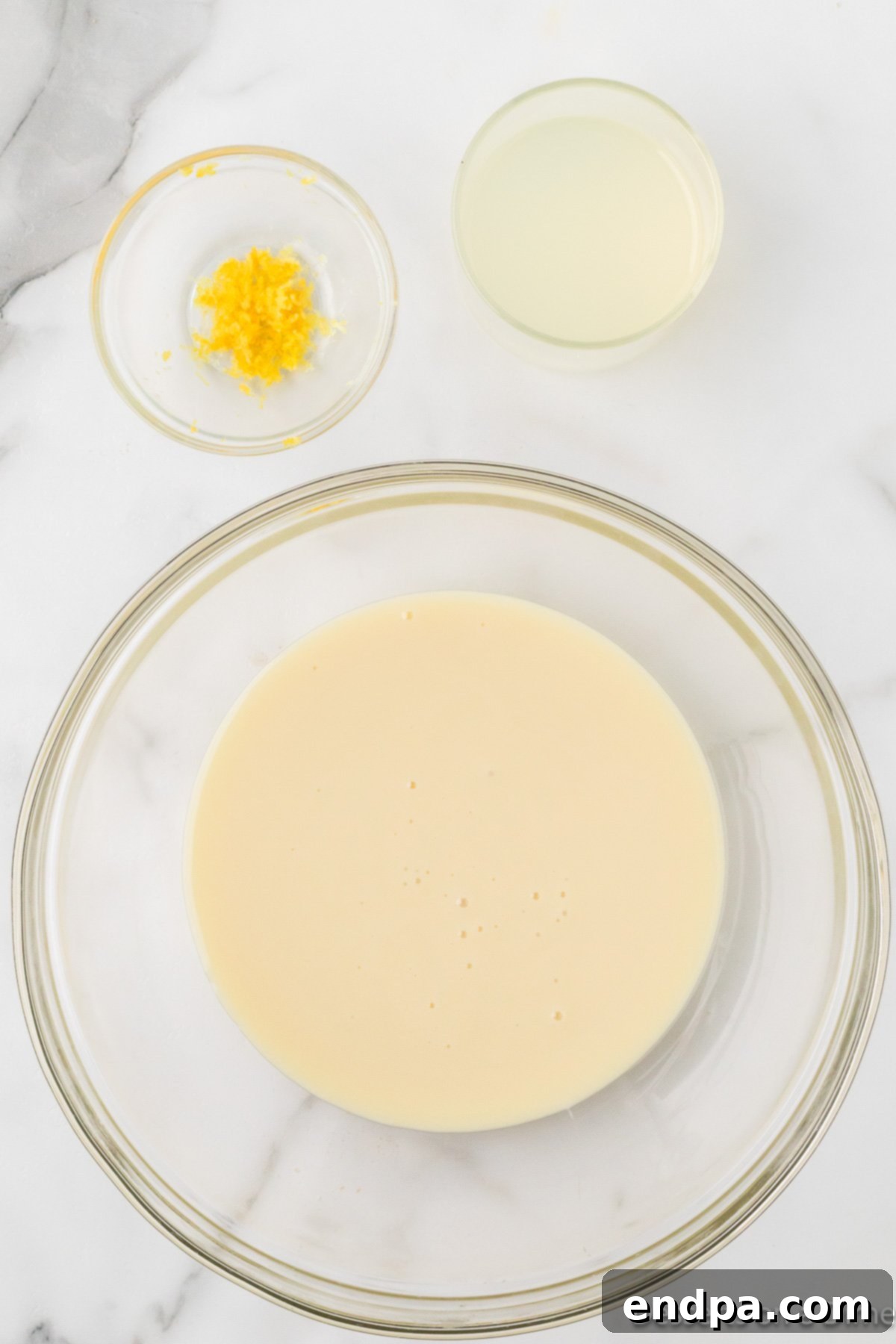 Cool Lemon Cloud Pie 7 A bowl containing sweetened condensed milk, lemonade concentrate, and lemon zest.