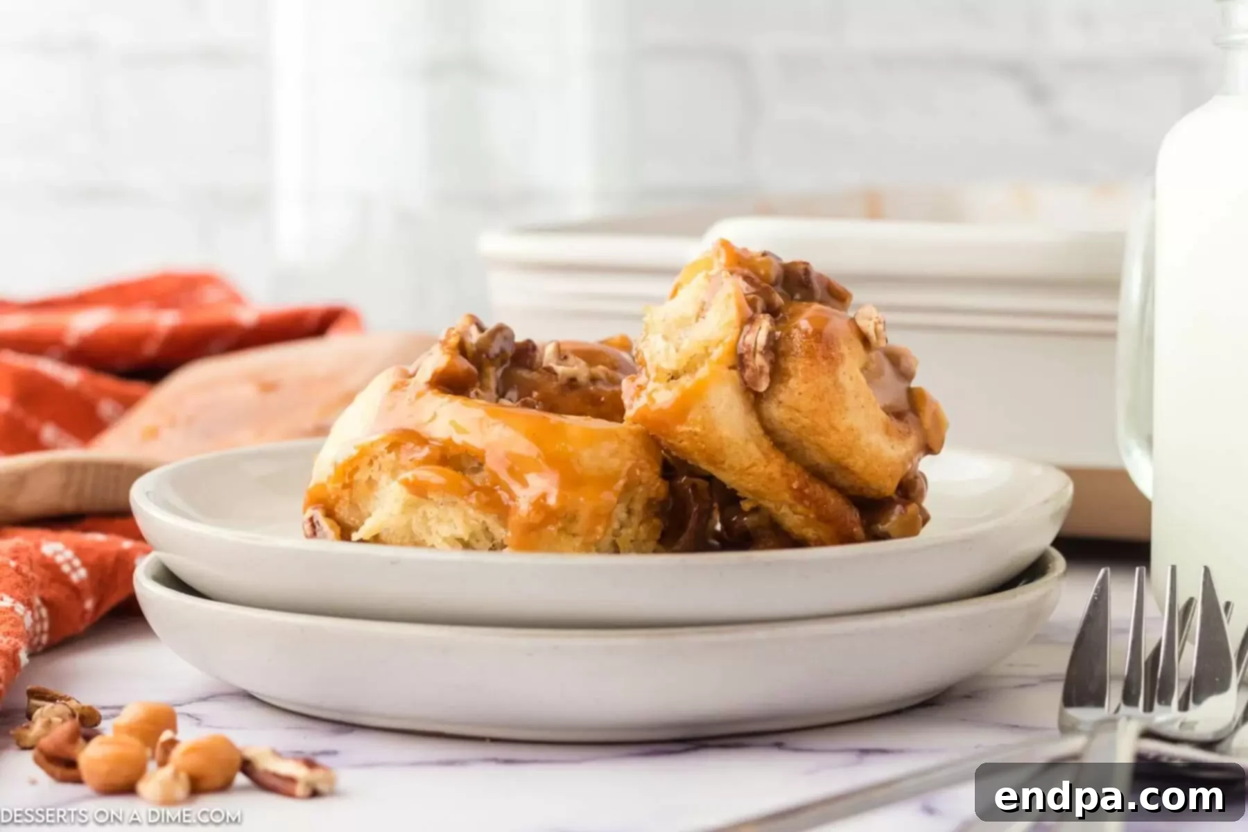 White plate with Caramel Pecan Cinnamon Rolls, showcasing their golden-brown edges, gooey caramel, and scattered pecans.