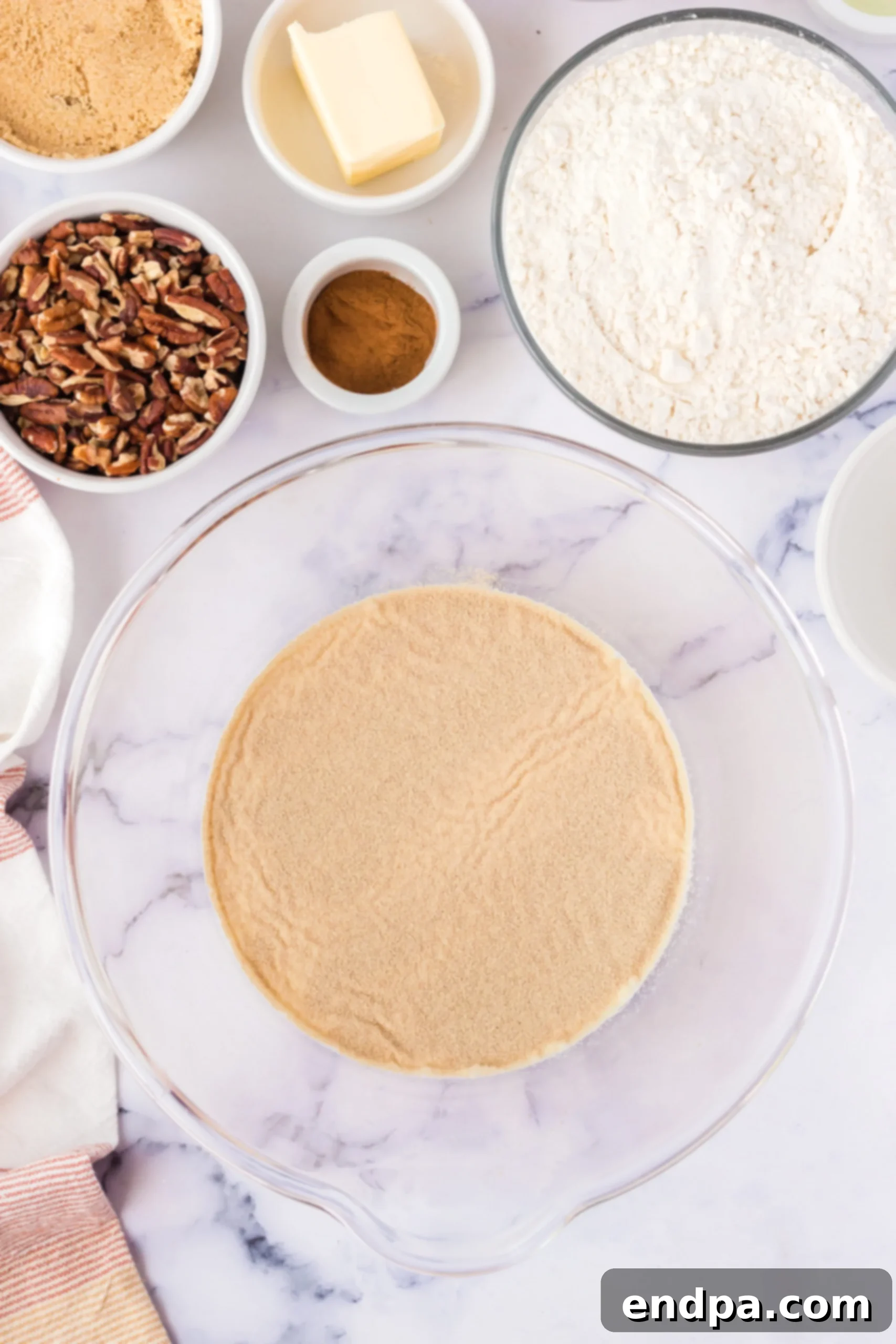 Warm milk and active dry yeast mixed in a glass bowl, starting to foam, indicating yeast activation.