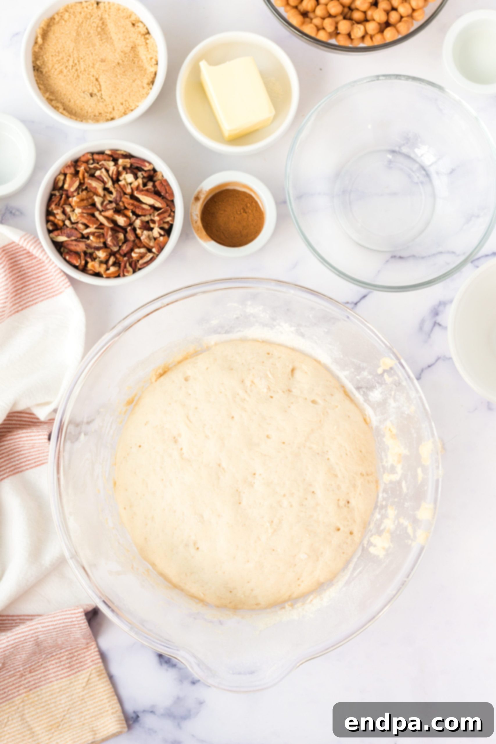 Dough resting and rising in a bowl covered with plastic wrap.