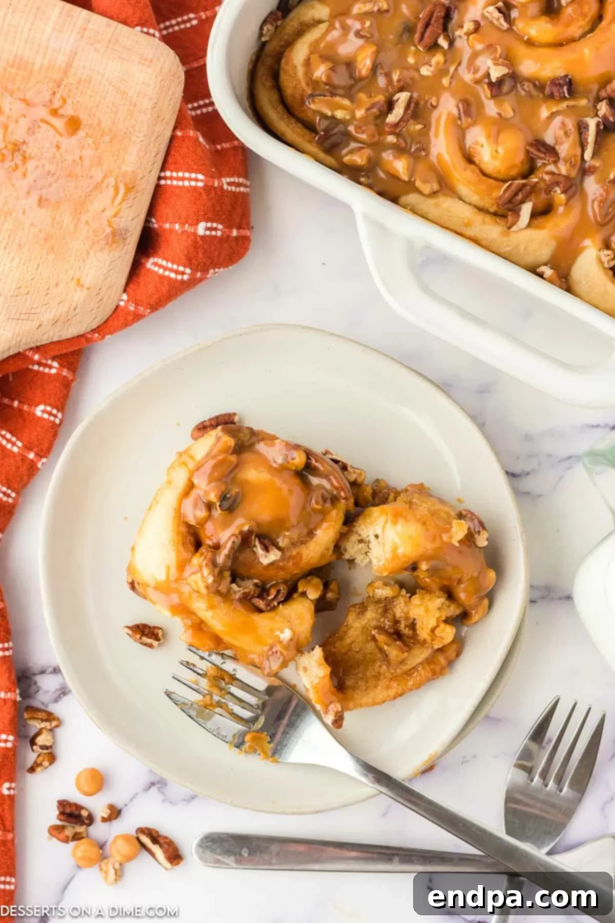 Individual Caramel Pecan Cinnamon Rolls on a white plate, showing the sticky glaze and generous pecan topping.