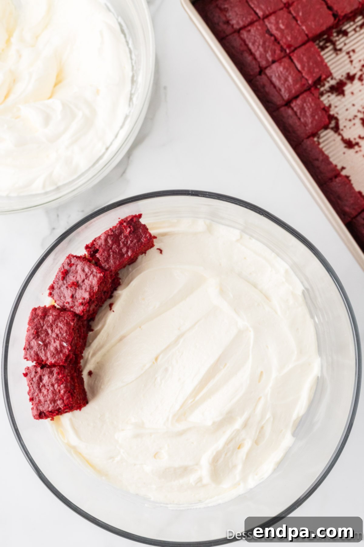 Crimson Velvet Dream 14 Cake cubes spread on top of pudding layer. More red cake cubes added on top of the creamy layer.