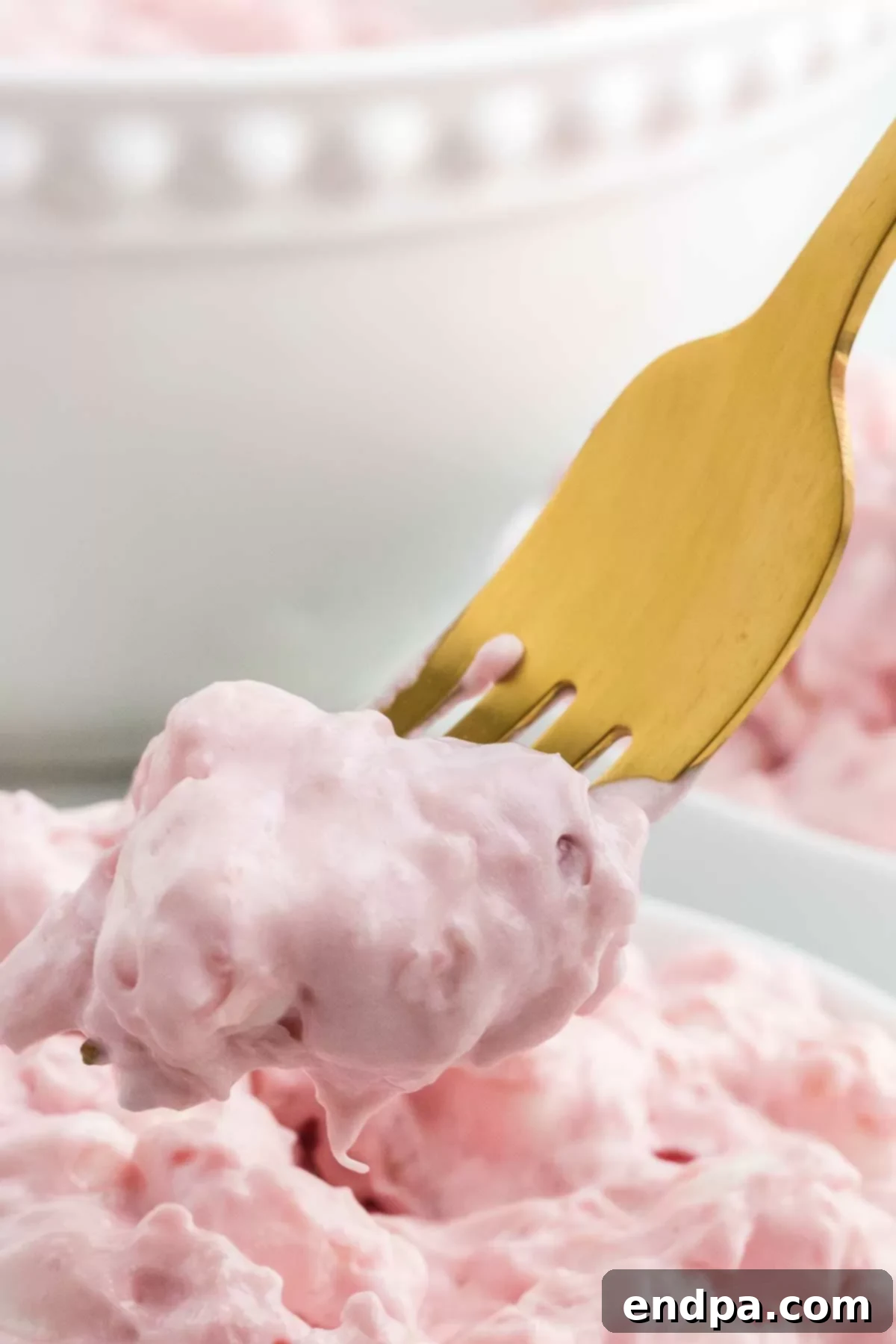 A beautiful bowl of Cherry Fluff recipe, with a spoon in it, ready to be enjoyed. 