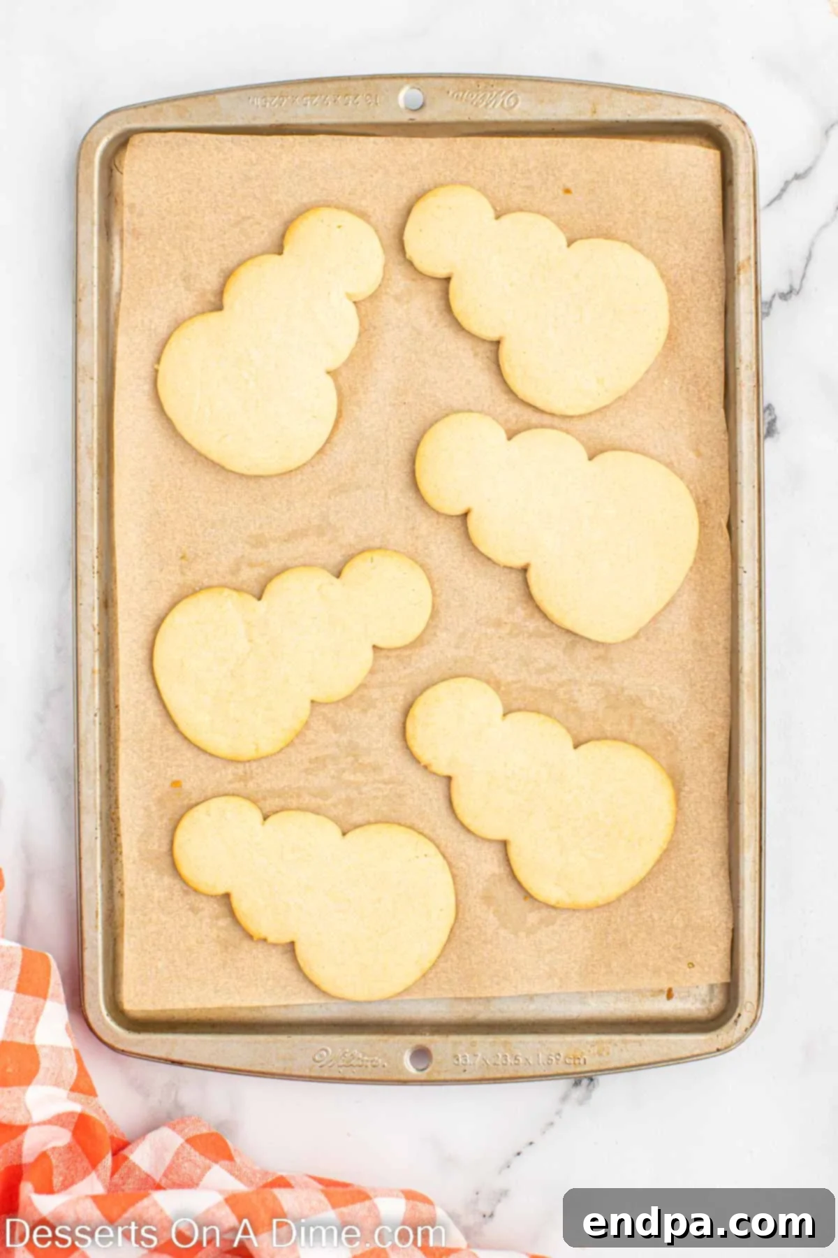 Baked snowman cookies cooling on a wire rack after being removed from the baking sheet.