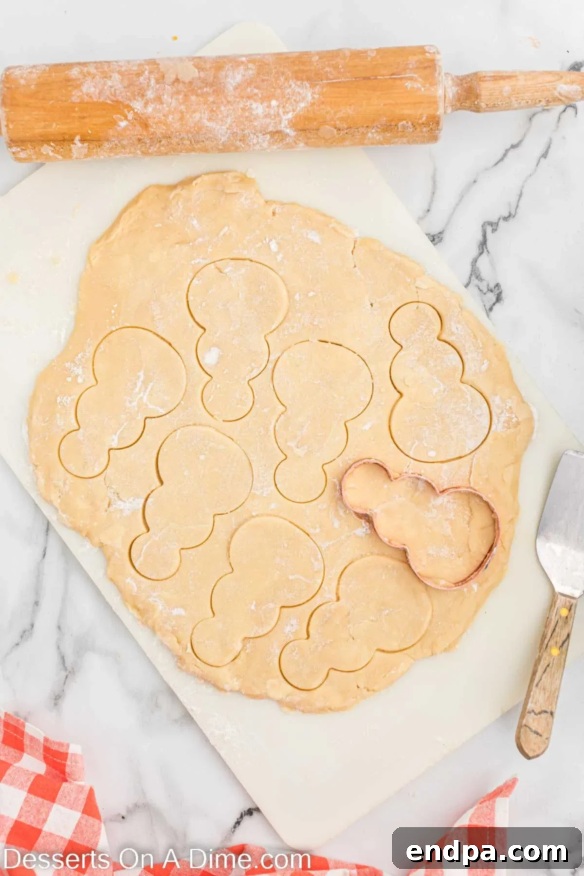 Rolled out cookie dough being cut into snowman shapes with a cookie cutter.