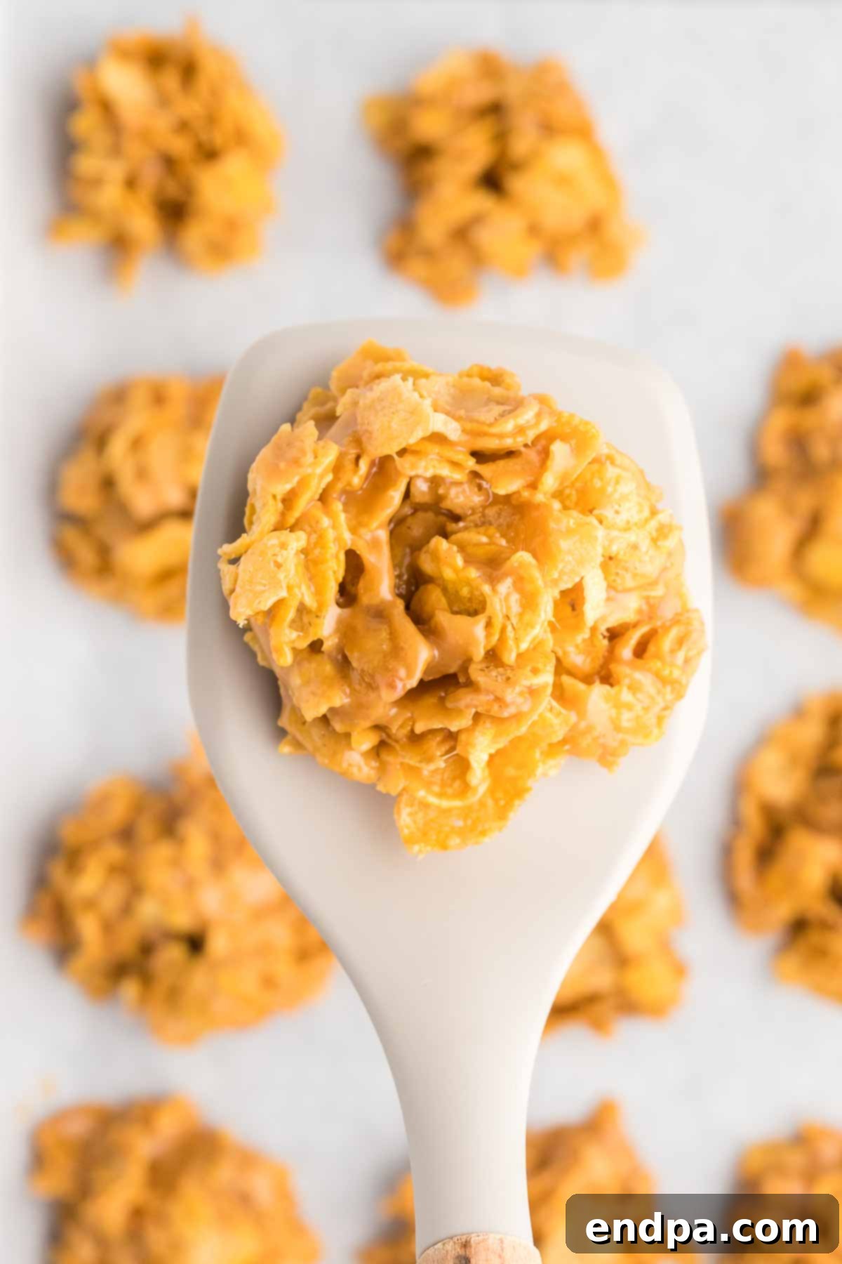 Cornflake Crunch Cookies 2 Close-up of golden brown cornflake cookies on parchment paper, highlighting their textured surface and delicious appeal.