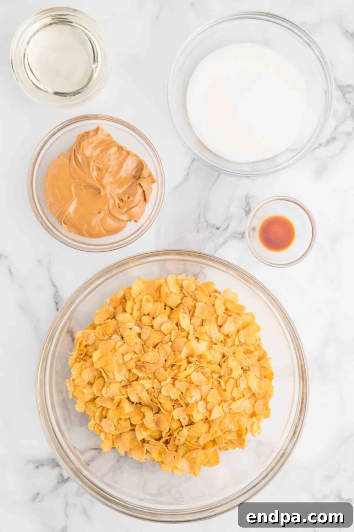 Cornflake Crunch Cookies 3 Ingredients laid out for cornflake cookies: cornflake cereal, granulated sugar, light corn syrup, creamy peanut butter, and vanilla extract.