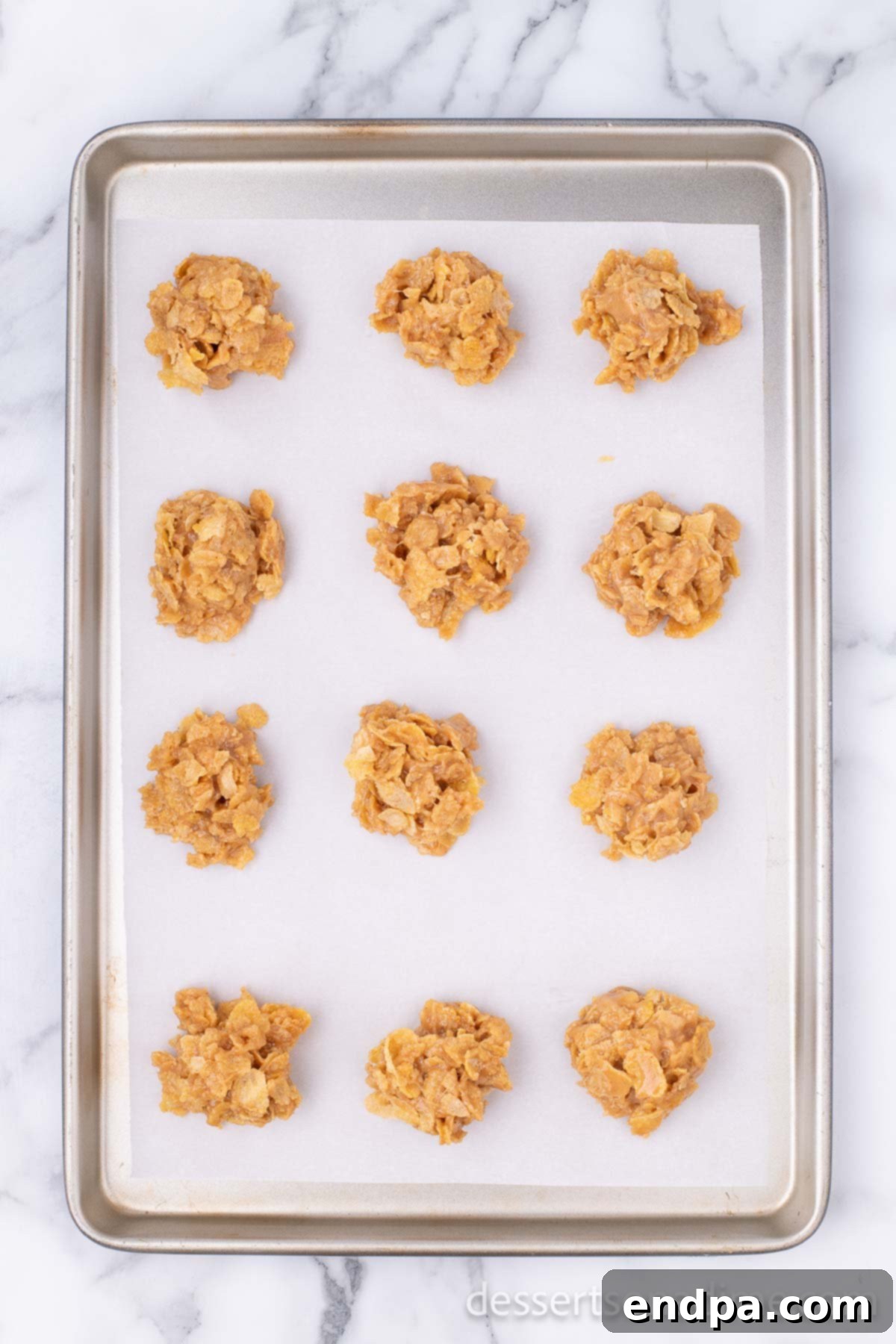Cornflake Crunch Cookies 7 Scooped cornflake cookies placed on a baking sheet lined with parchment paper, cooling and setting.