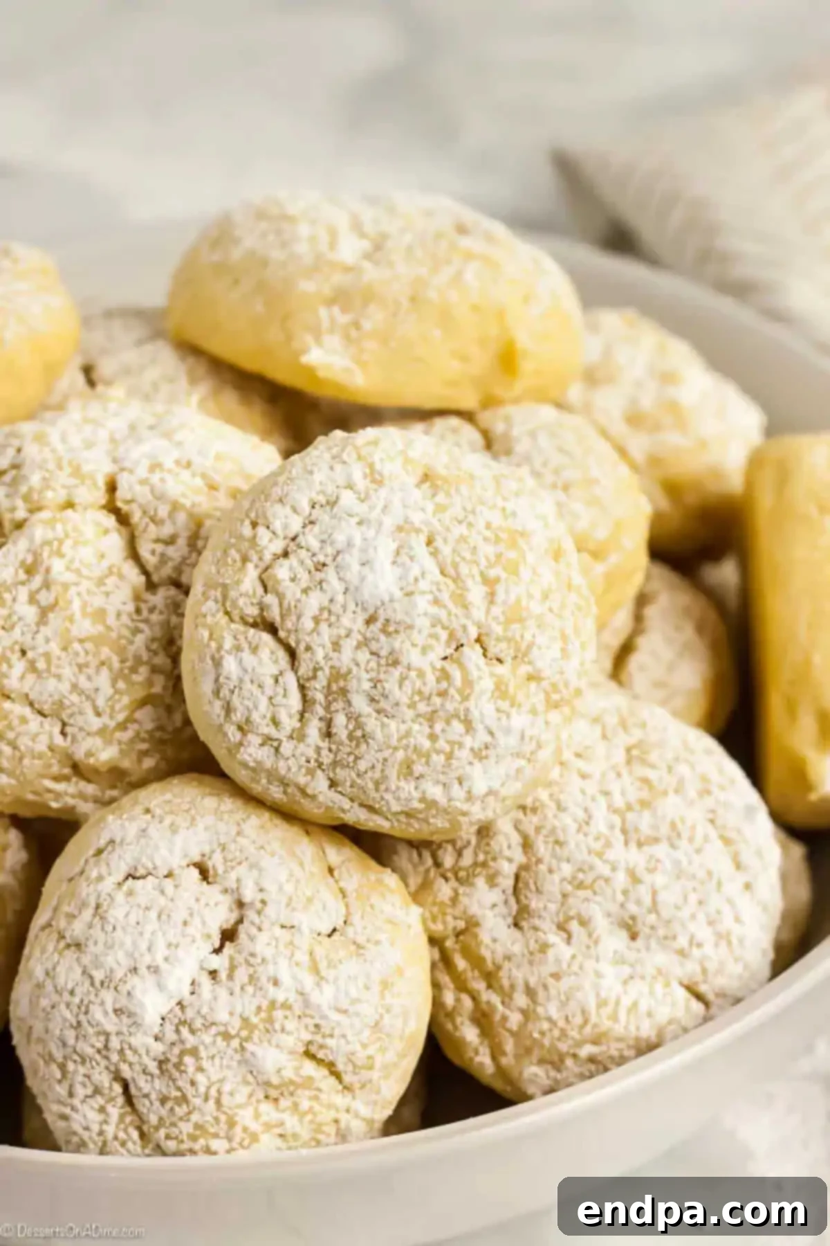 Velvety Cream Cheese Cookies 2 Cream Cheese Cookies topped with powdered sugar in a large white bowl.