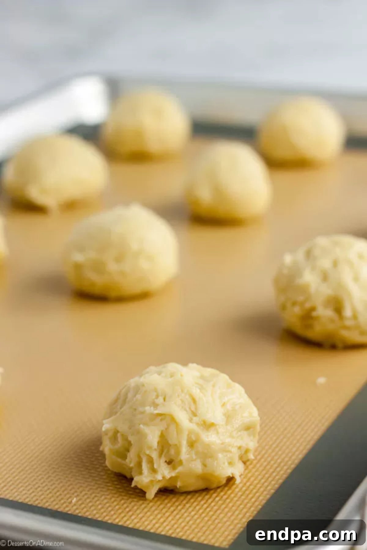 Velvety Cream Cheese Cookies 7 Cream cheese cookie dough formed into dough balls and placed on a baking sheet.
