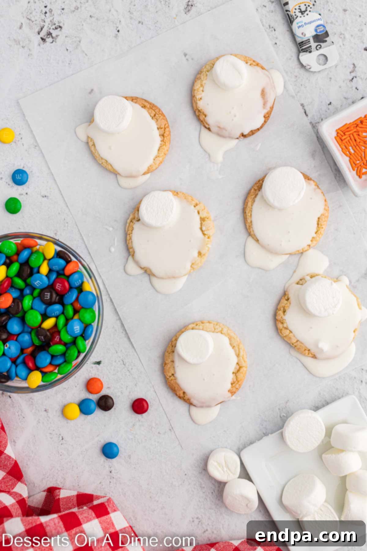 Whimsical Melted Snowman Treats 5 Icing spread on cookies. Freshly baked sugar cookies are being generously frosted with white royal icing, creating a drippy, melted effect around the edges on parchment paper.