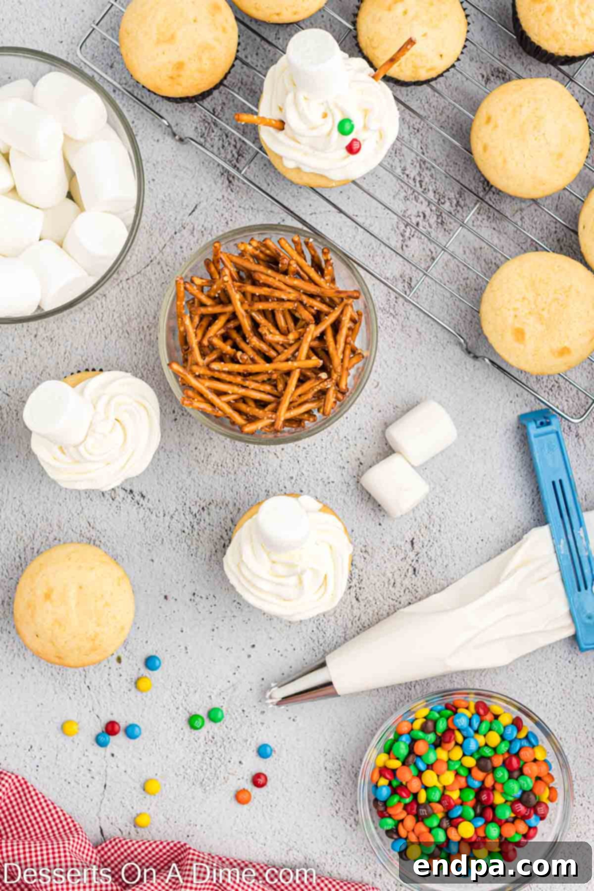 A bowl of pretzel sticks next to cupcakes being frosted, showing the start of the decorating process.