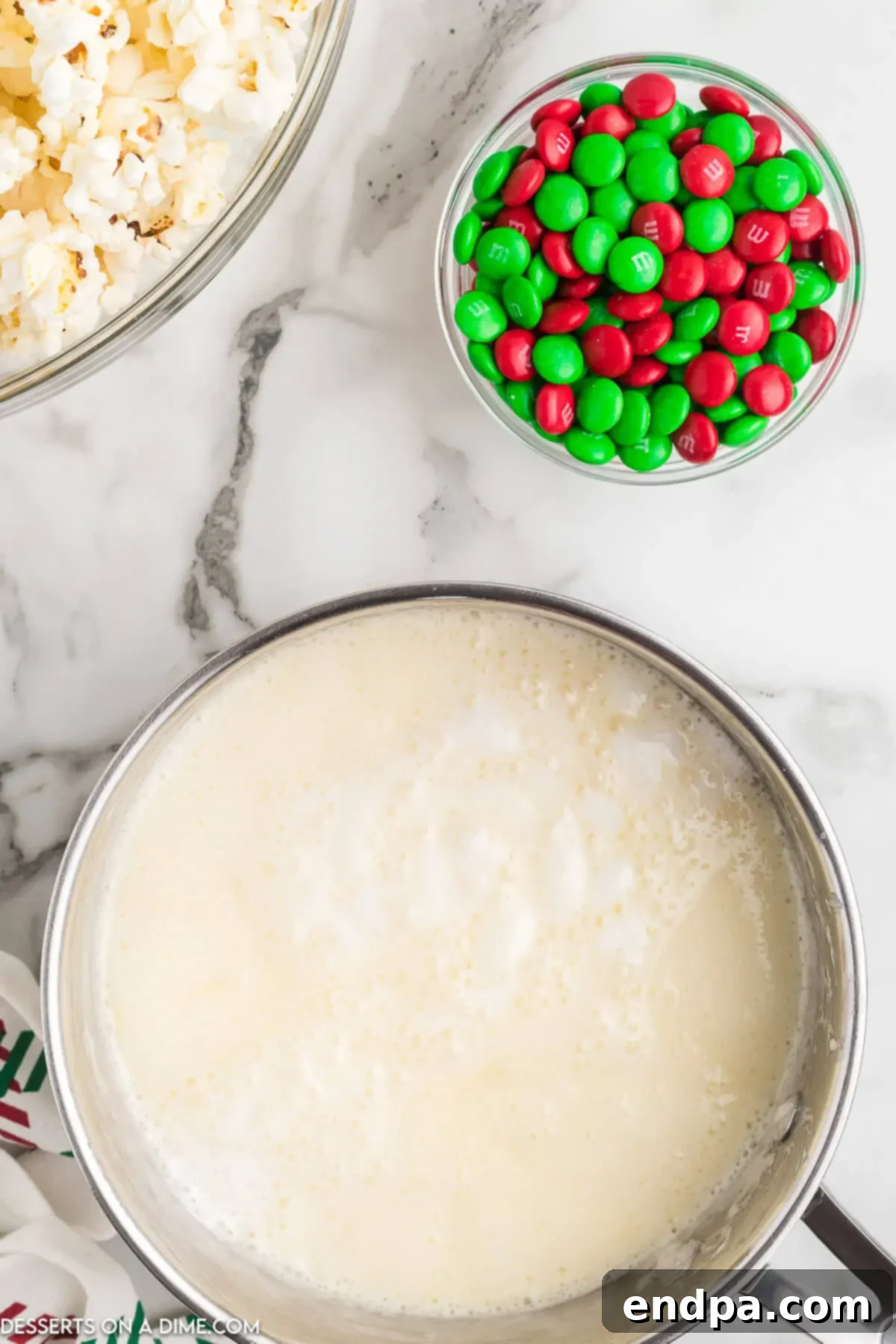 Holiday Popcorn Ball Delight 4 A saucepan on a stovetop, containing a mixture of sugar, corn syrup, butter, and salt, boiling vigorously and being continuously stirred with a wooden spoon.
