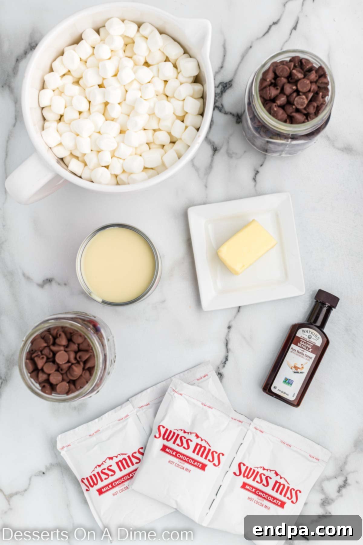 Various ingredients for Hot Chocolate Fudge including semi-sweet and milk chocolate chips, butter, sweetened condensed milk, hot cocoa mix, vanilla, and mini marshmallows.
