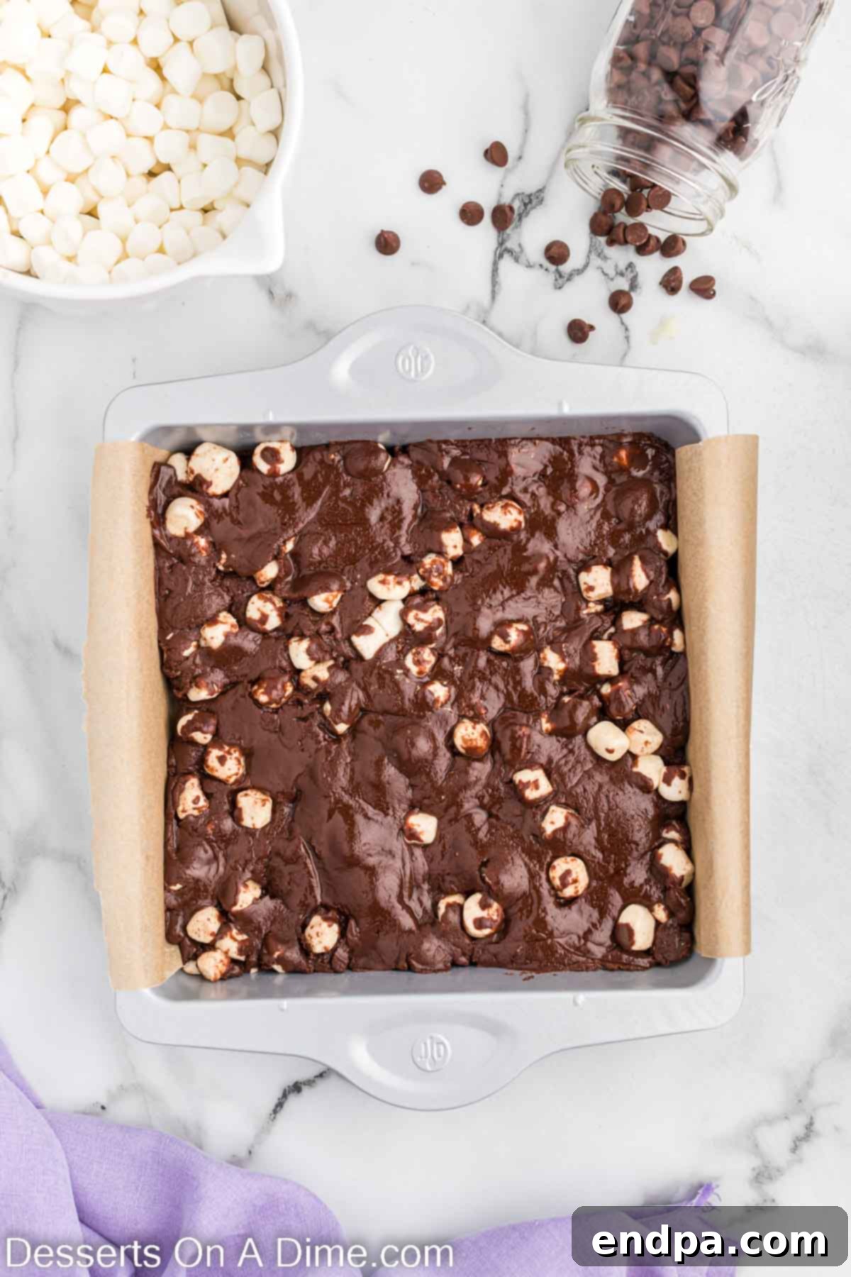 Fudge mixture being poured and spread evenly into the prepared baking dish.