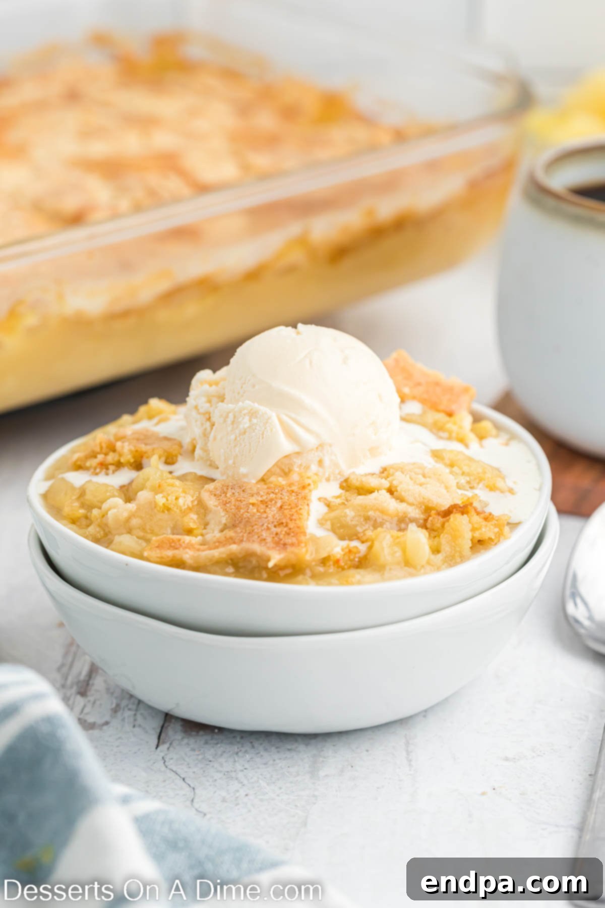 Pineapple dump cake in a bowl topped with ice cream. 