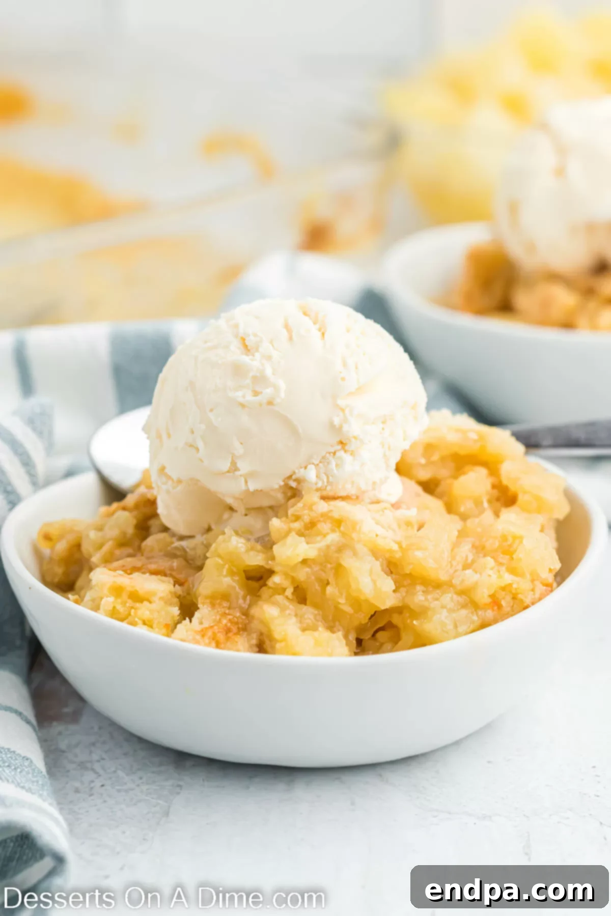 Pineapple dump cake in a bowl topped with ice cream. 