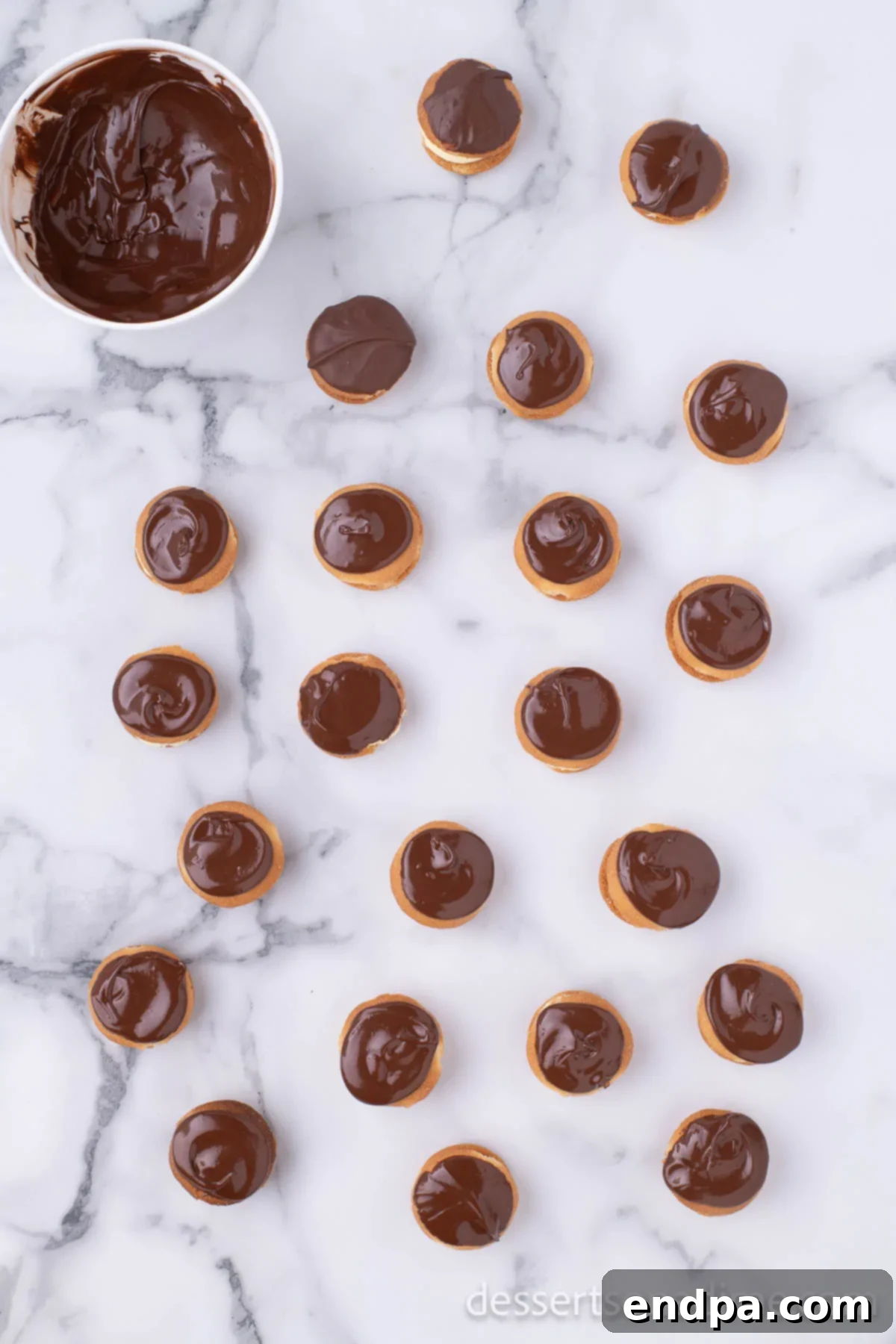 Eclair Cookie Fusion 9 A stack of partially assembled Eclair Cookies, illustrating the pudding layer and a top vanilla wafer being carefully dipped into the bowl of melted chocolate.