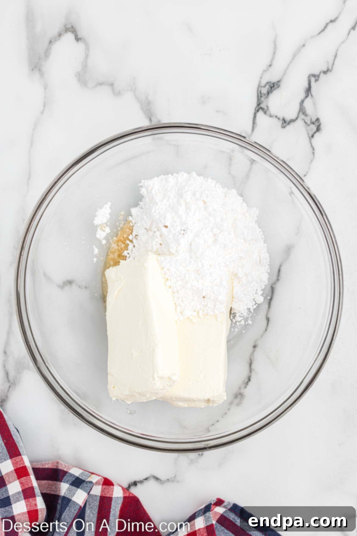Mixing bowl with cream cheese, powdered sugar, and vanilla. 