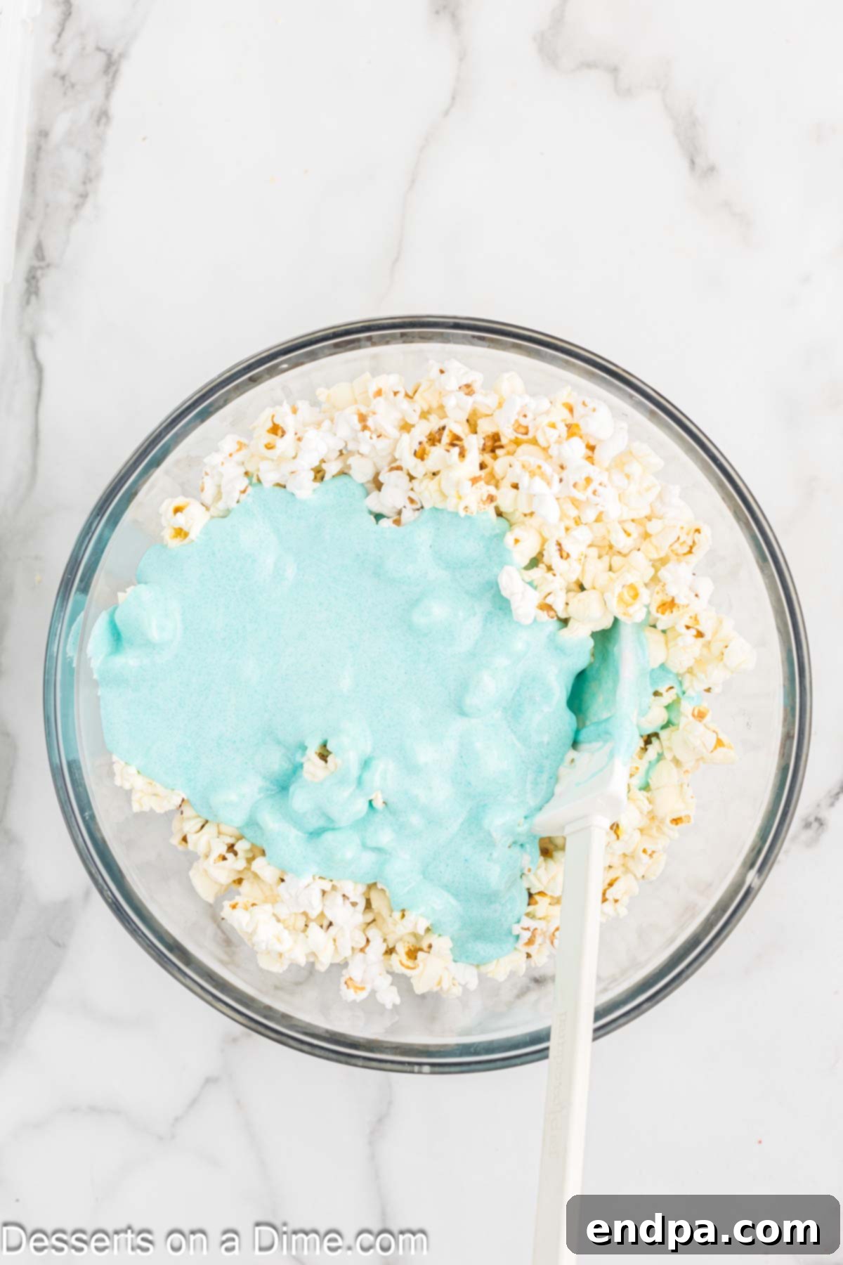 Marshmallow mixture poured over popcorn in a bowl.