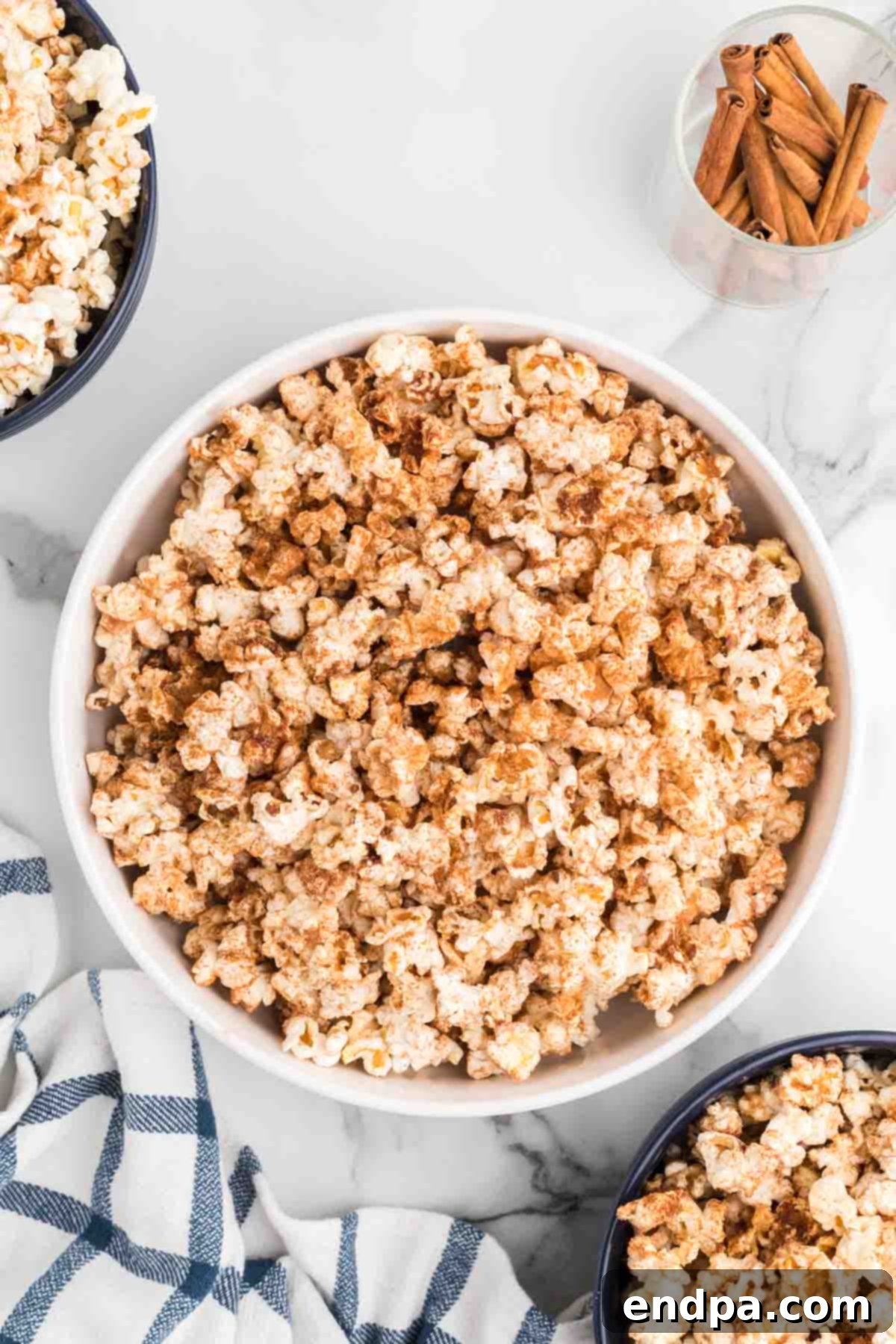 A large bowl of golden brown Cinnamon Toast Crunch Popcorn, garnished with extra cinnamon sugar, ready to be enjoyed as a sweet and salty snack.