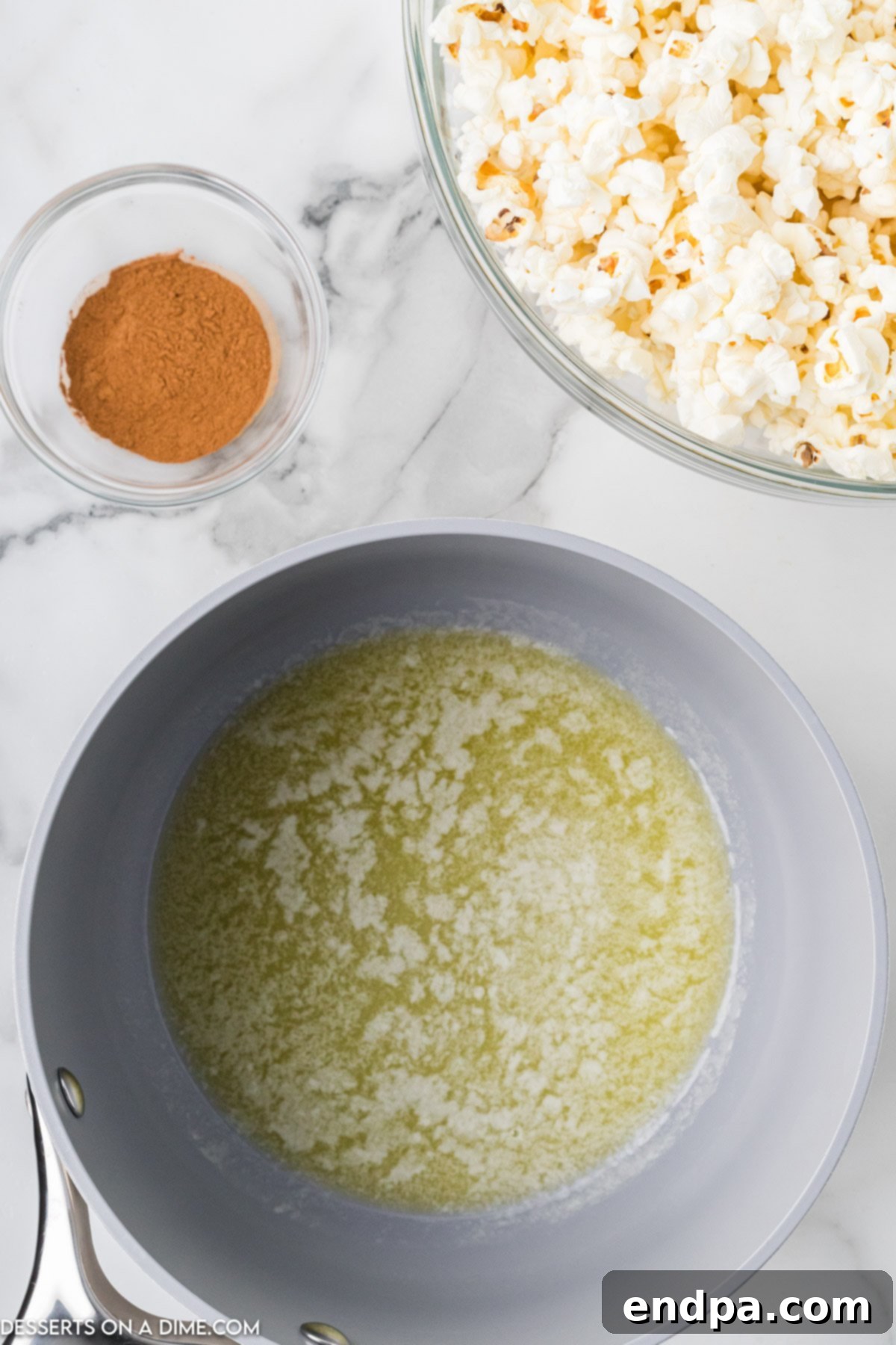 A saucepan on a stovetop with melted butter, shimmering and ready to be drizzled.