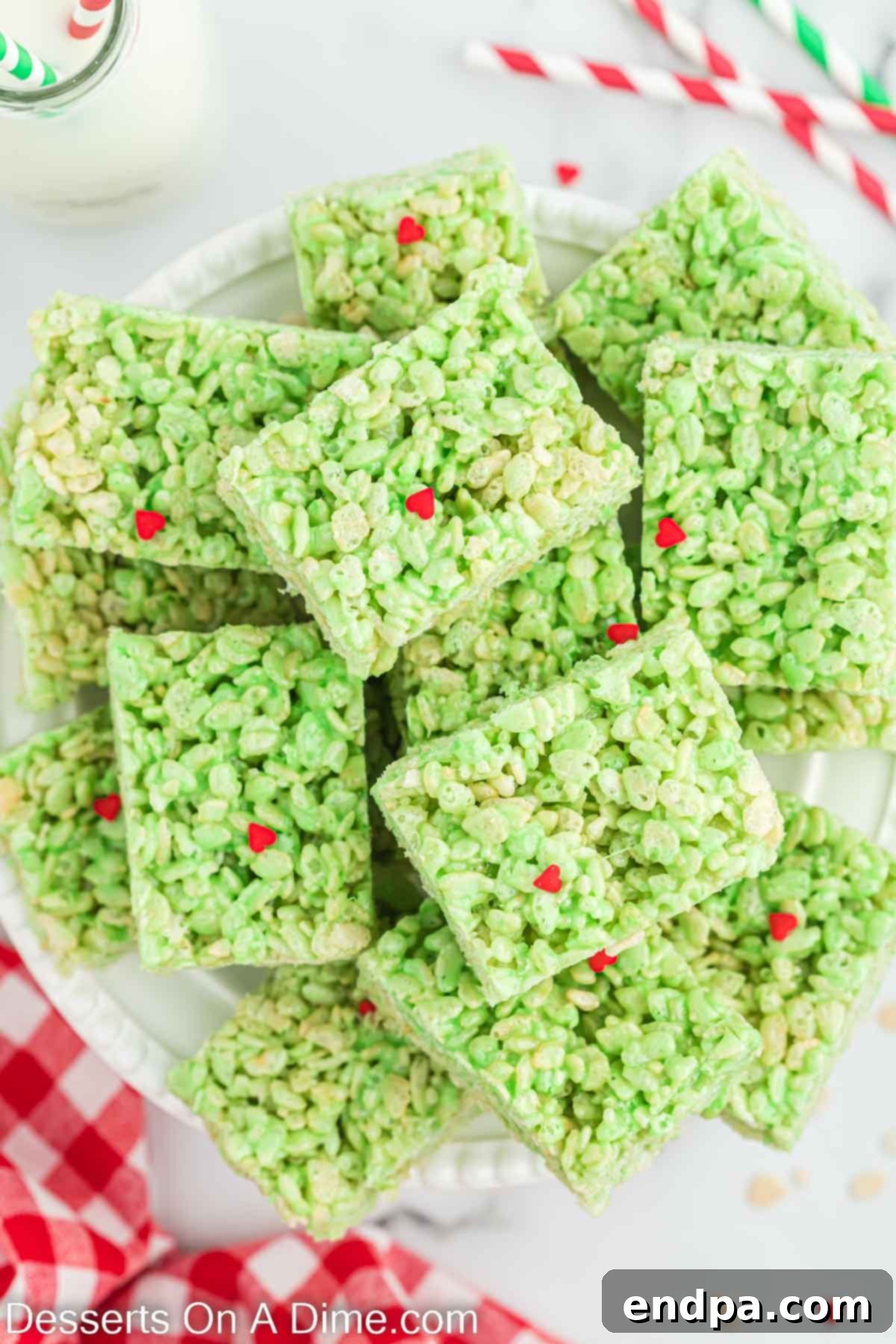 Grinch Rice Krispie Treats cut into squares and stacked, showcasing their vibrant green color and red heart sprinkles.