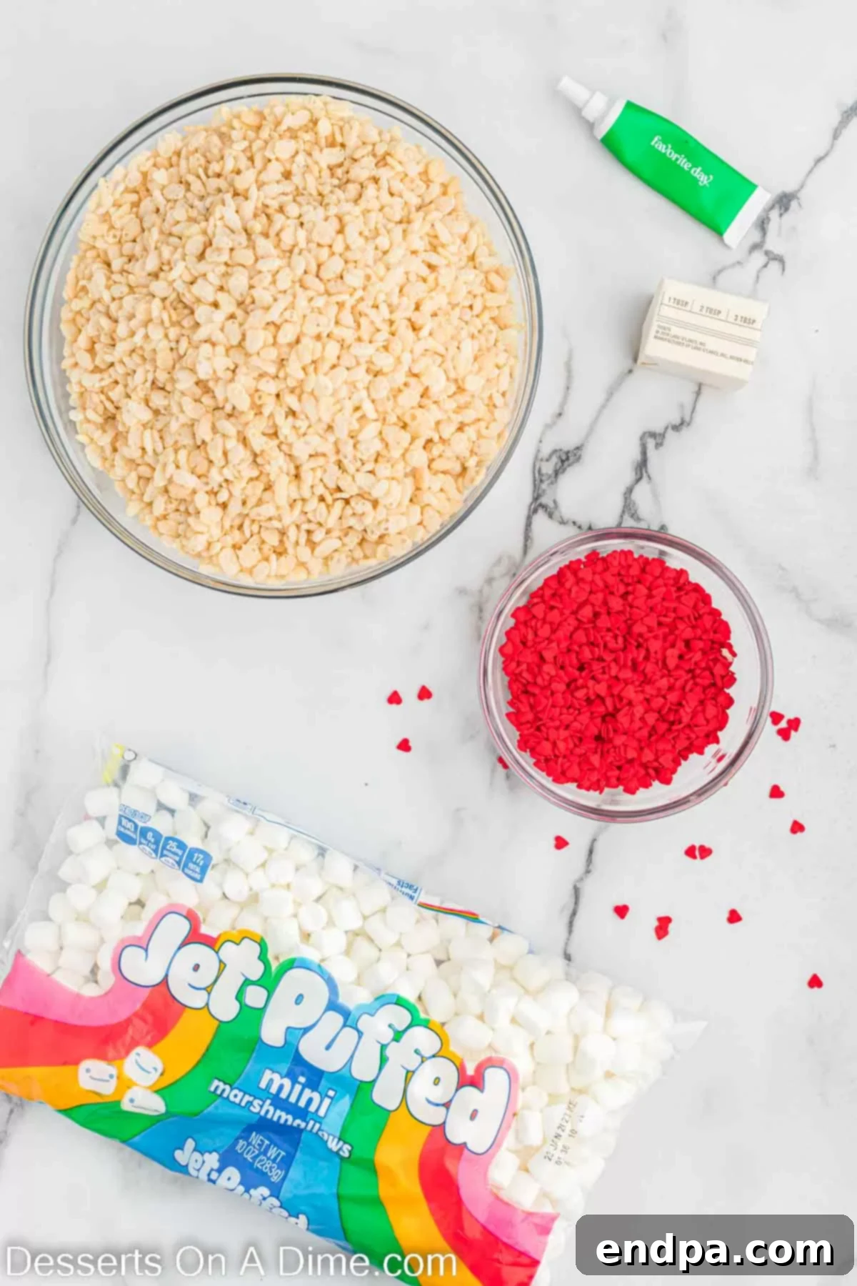 Ingredients laid out: Rice Krispie cereal, butter, marshmallows, green food coloring, and red heart sprinkles.