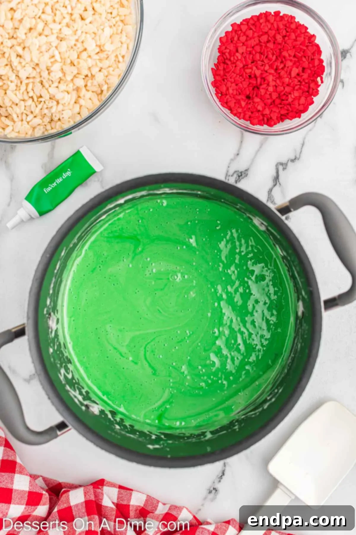 Saucepan with green food coloring added to the marshmallow and butter mixture, now combined to a vibrant green.
