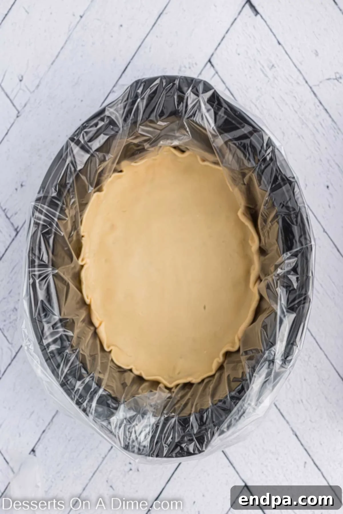 Pie crust in crock pot. A raw pie crust perfectly fitted into the bottom of a slow cooker.