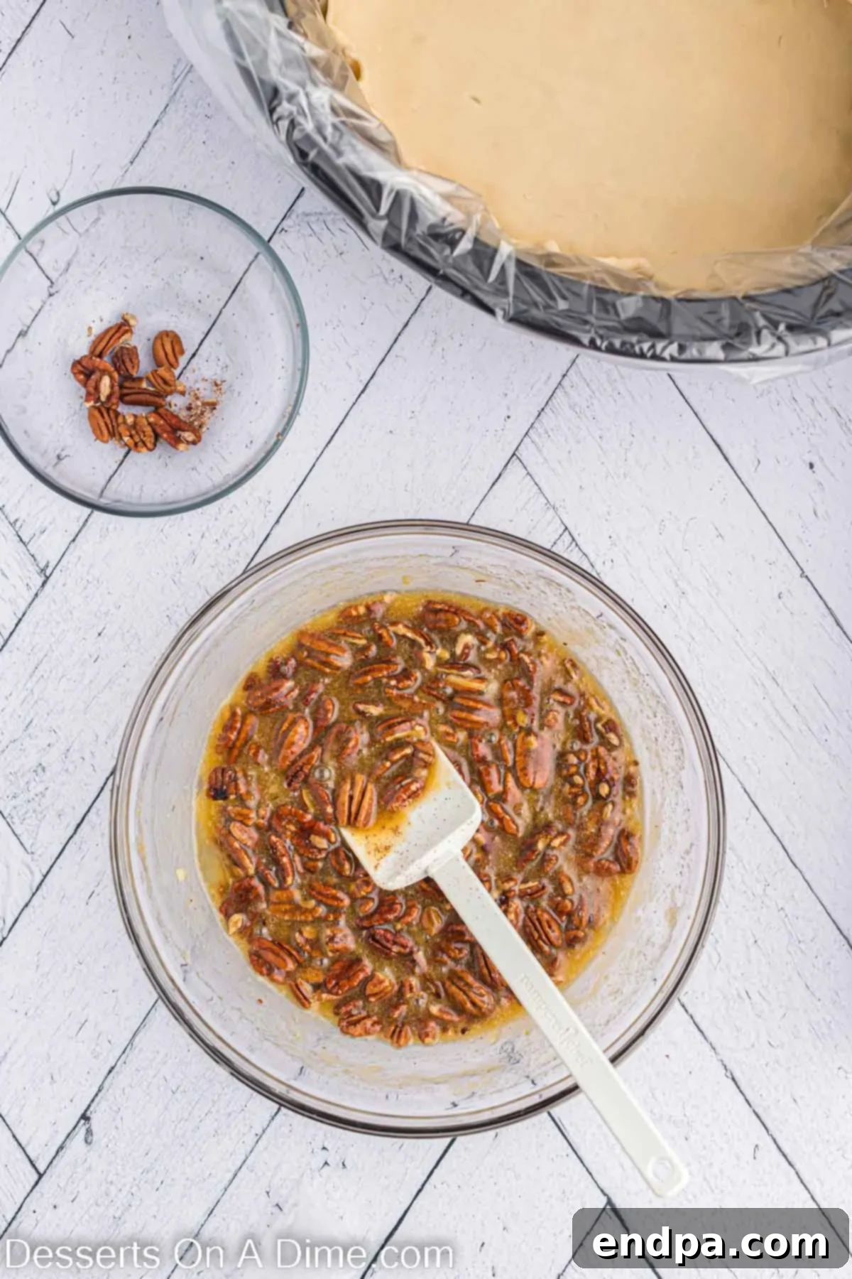 Pecan mixture combined in a bowl. A mixing bowl filled with the pecan pie filling ingredients, including whole pecans, before being poured into the crust.